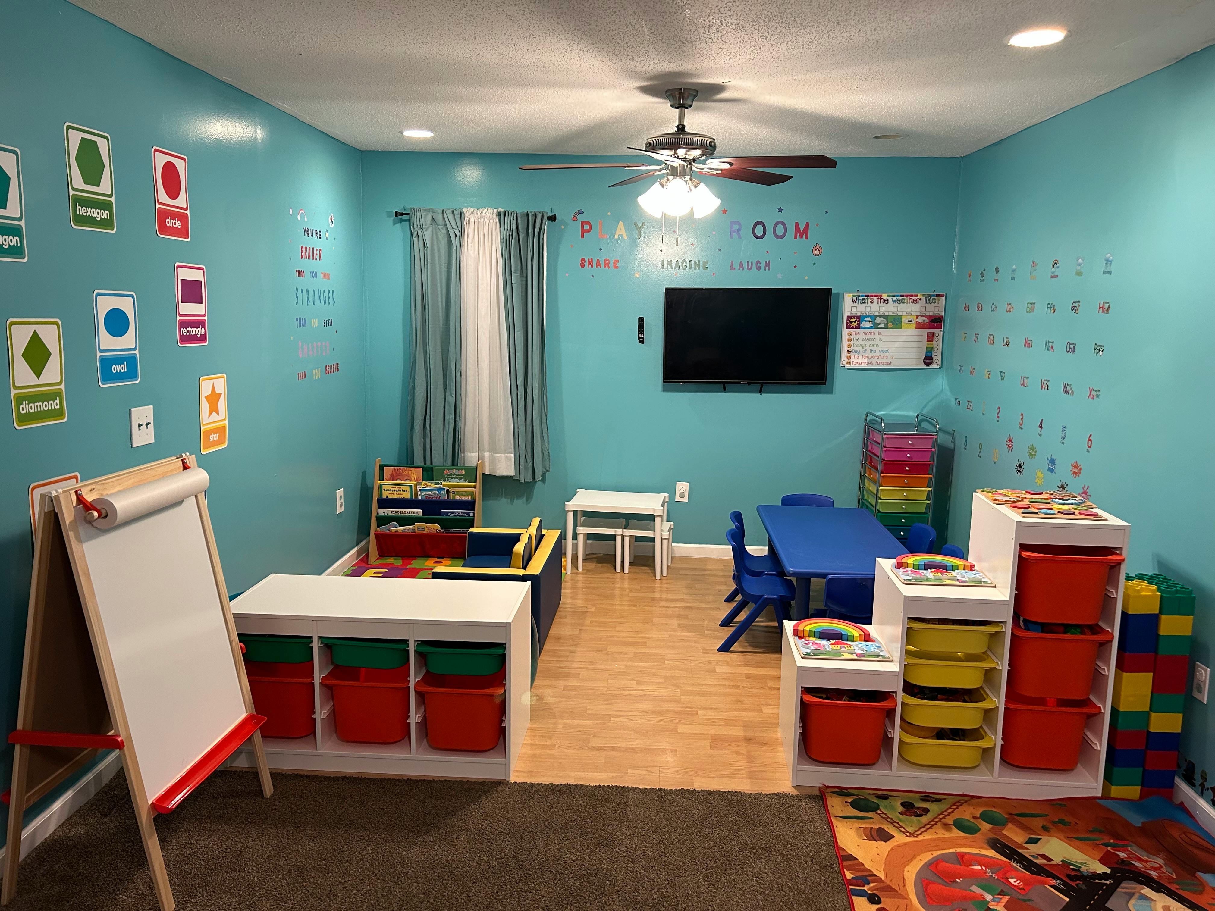 Playroom with blue walls, small tables, chairs, and toy storage