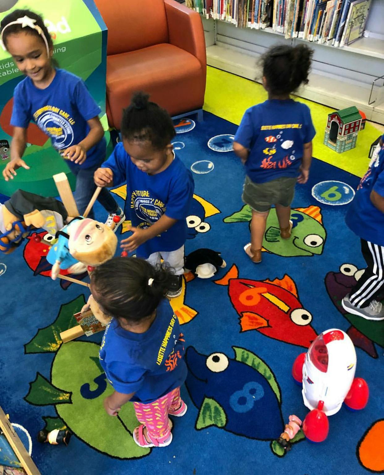 Children playing on a blue rug with fish designs