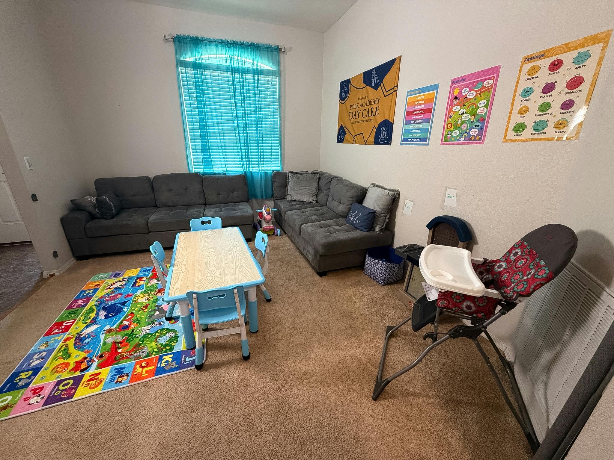 Living room with a gray sectional sofa, child's table and chairs, and high chair