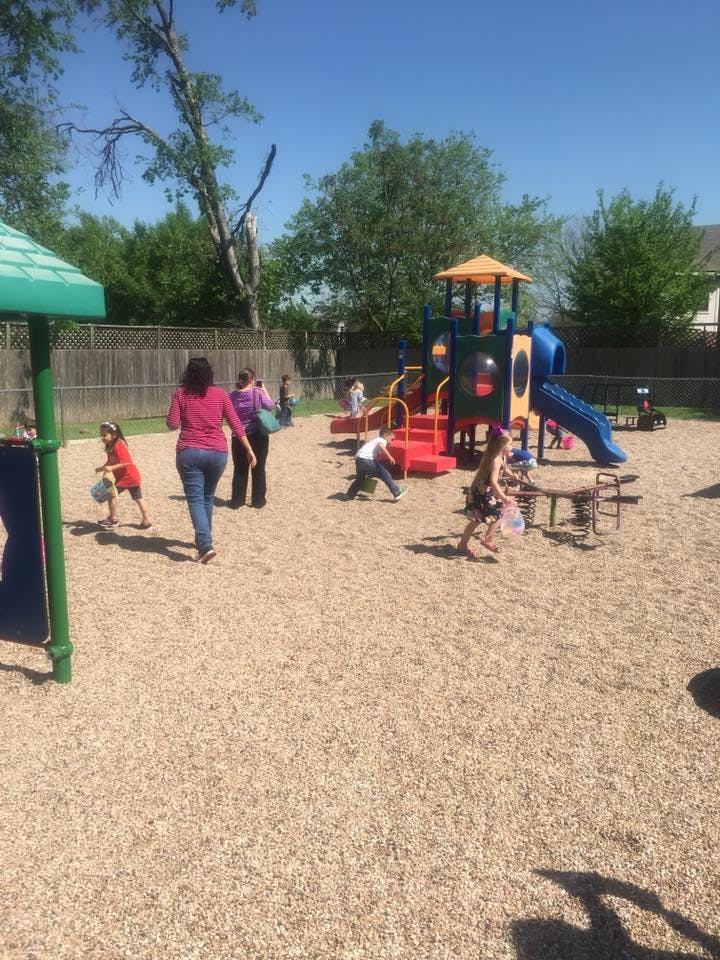 People and children on a playground with play structures