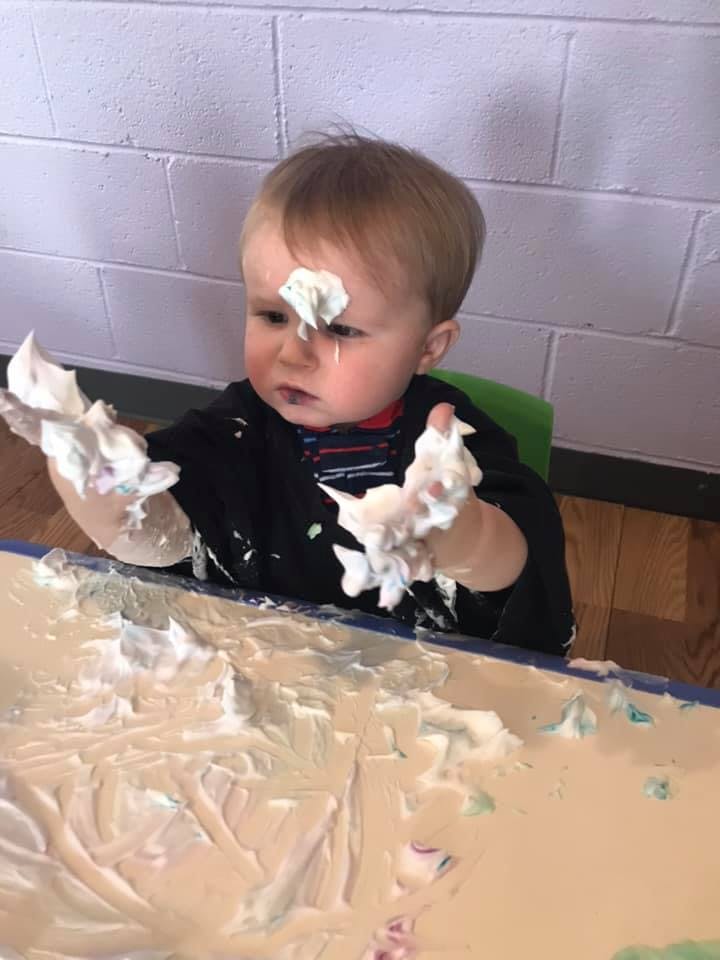 Child playing with shaving cream on a table