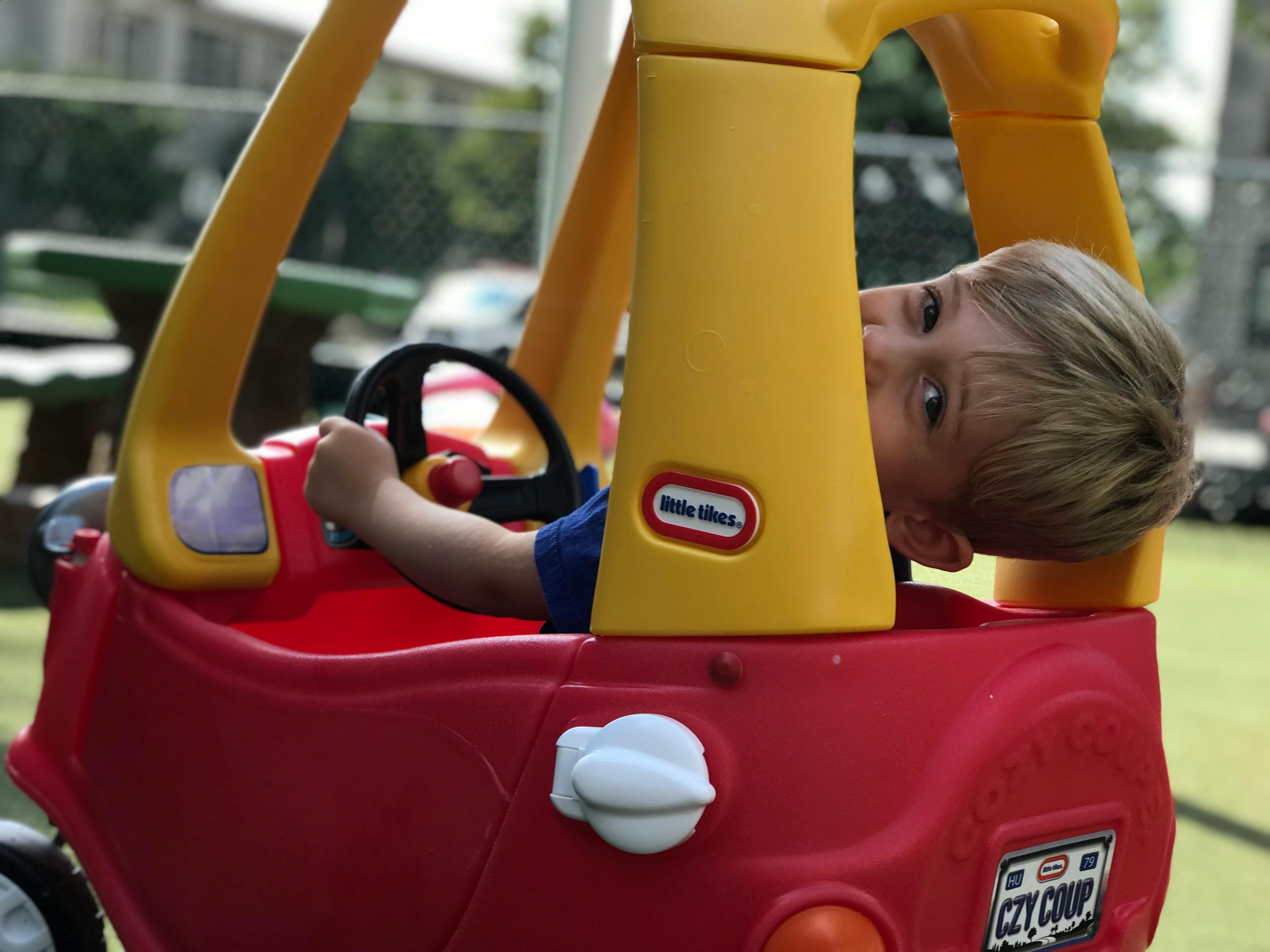 Child in a red toy car