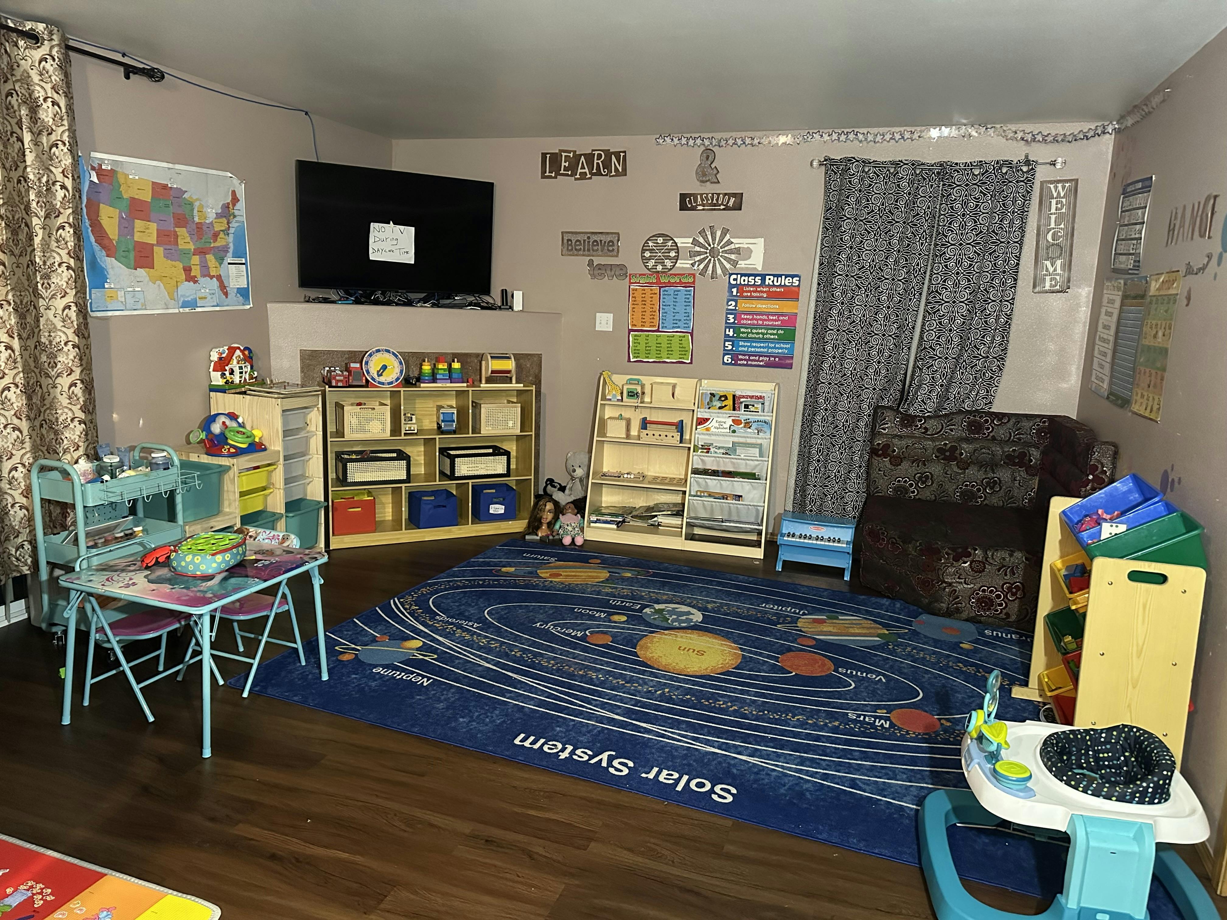 Playroom with a solar system rug, small table and chairs, and shelves with shelves of shelves