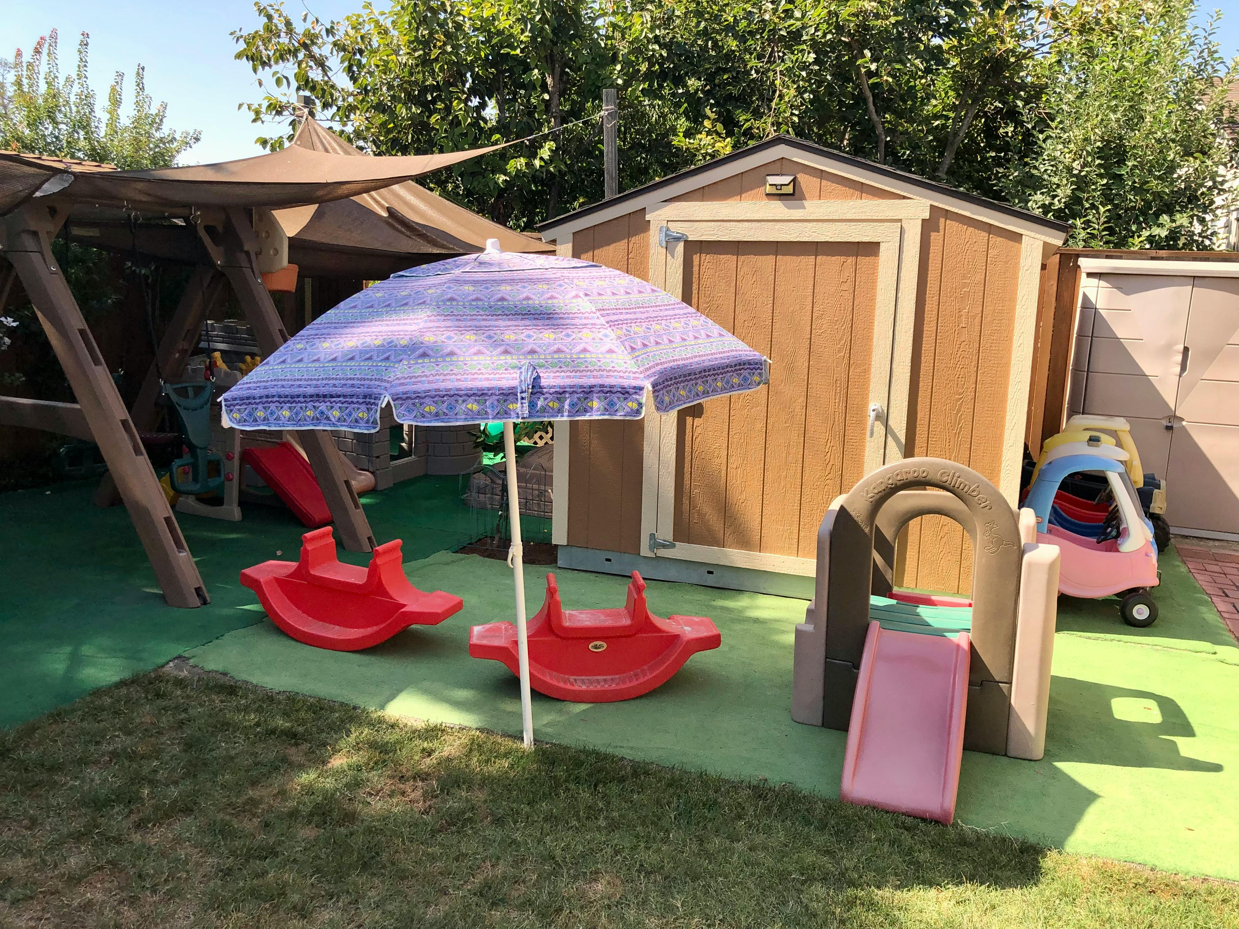 Playground with a wooden playset, red seesaws, and a small slide