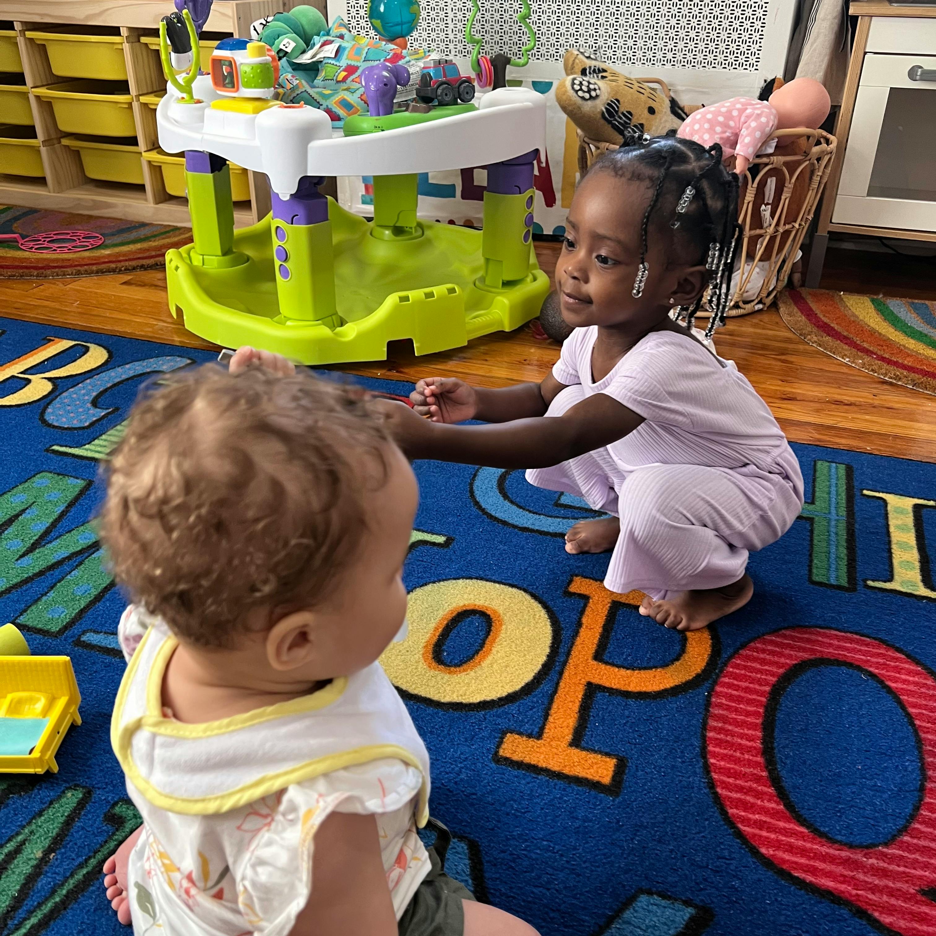Two children playing on a colorful alphabet rug
