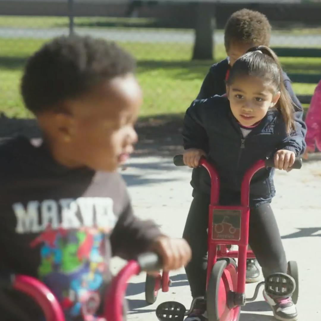 Two children riding tricycles outdoors