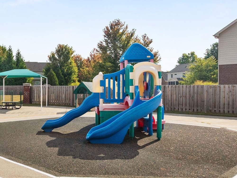 Colorful playground structure with multiple slides on a dark soft surface