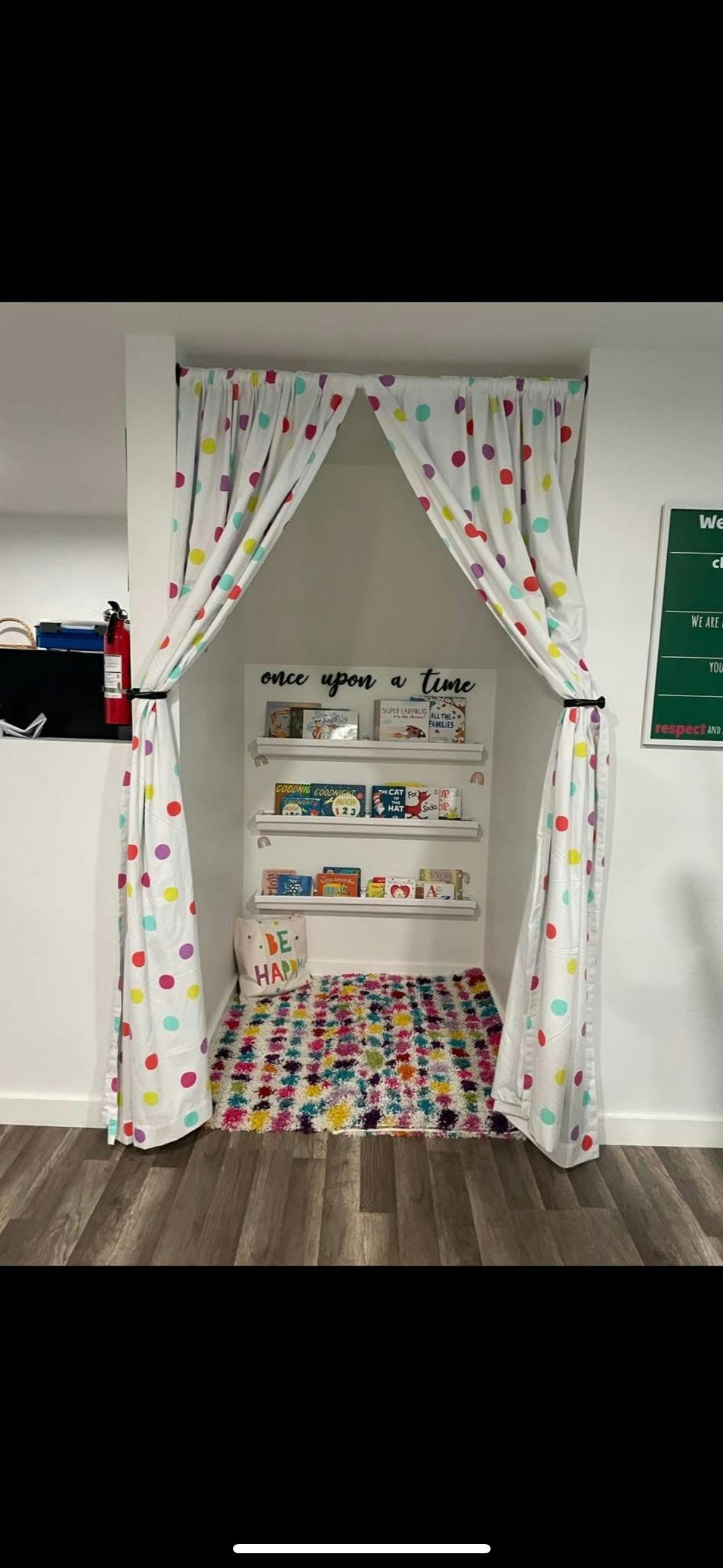 Reading nook with polka dot curtains, shelves of books, and a colorful rug