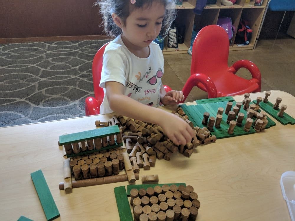 Child playing with wooden blocks and green pieces on a table