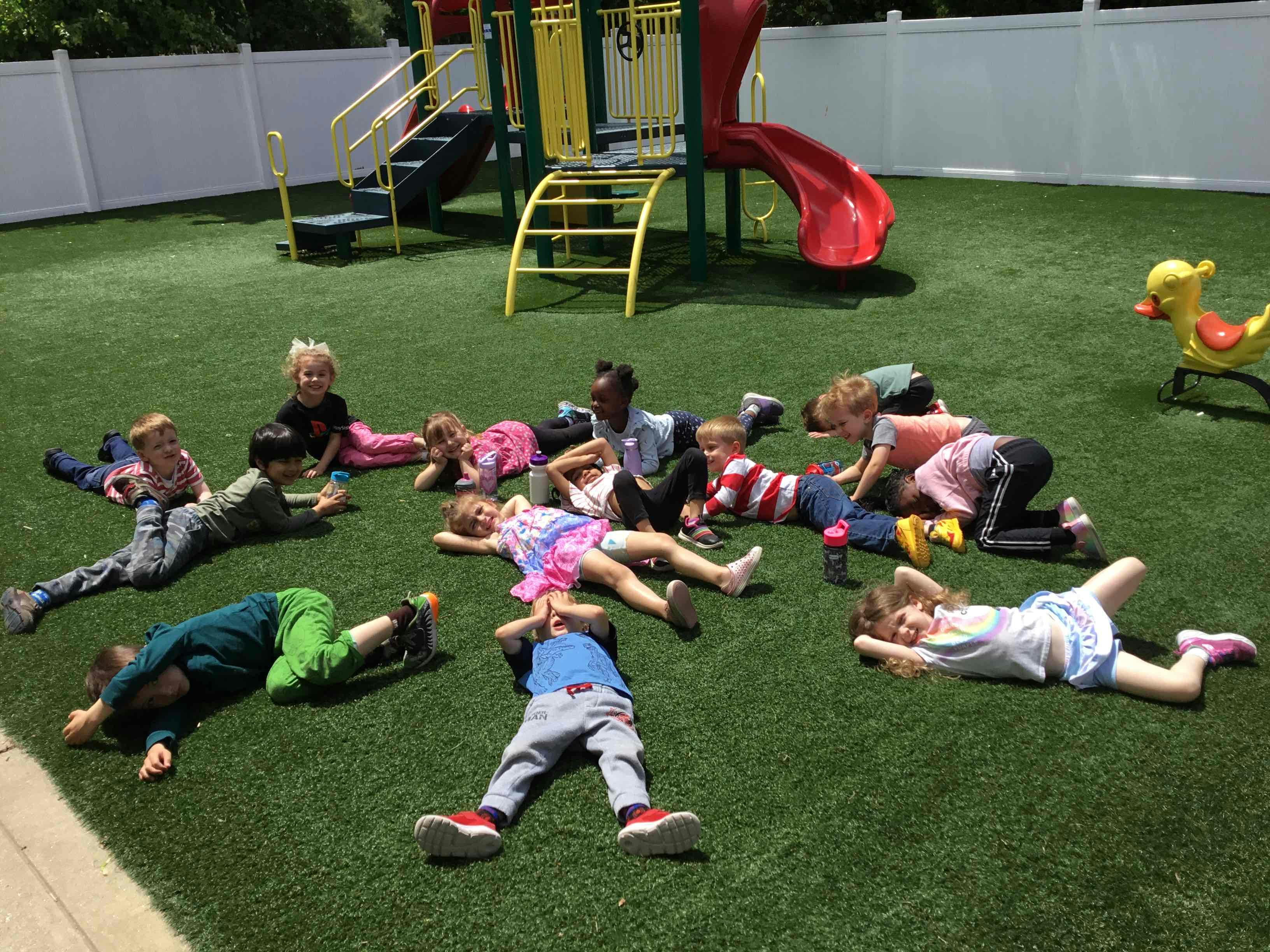 Children lying on artificial grass on a playground