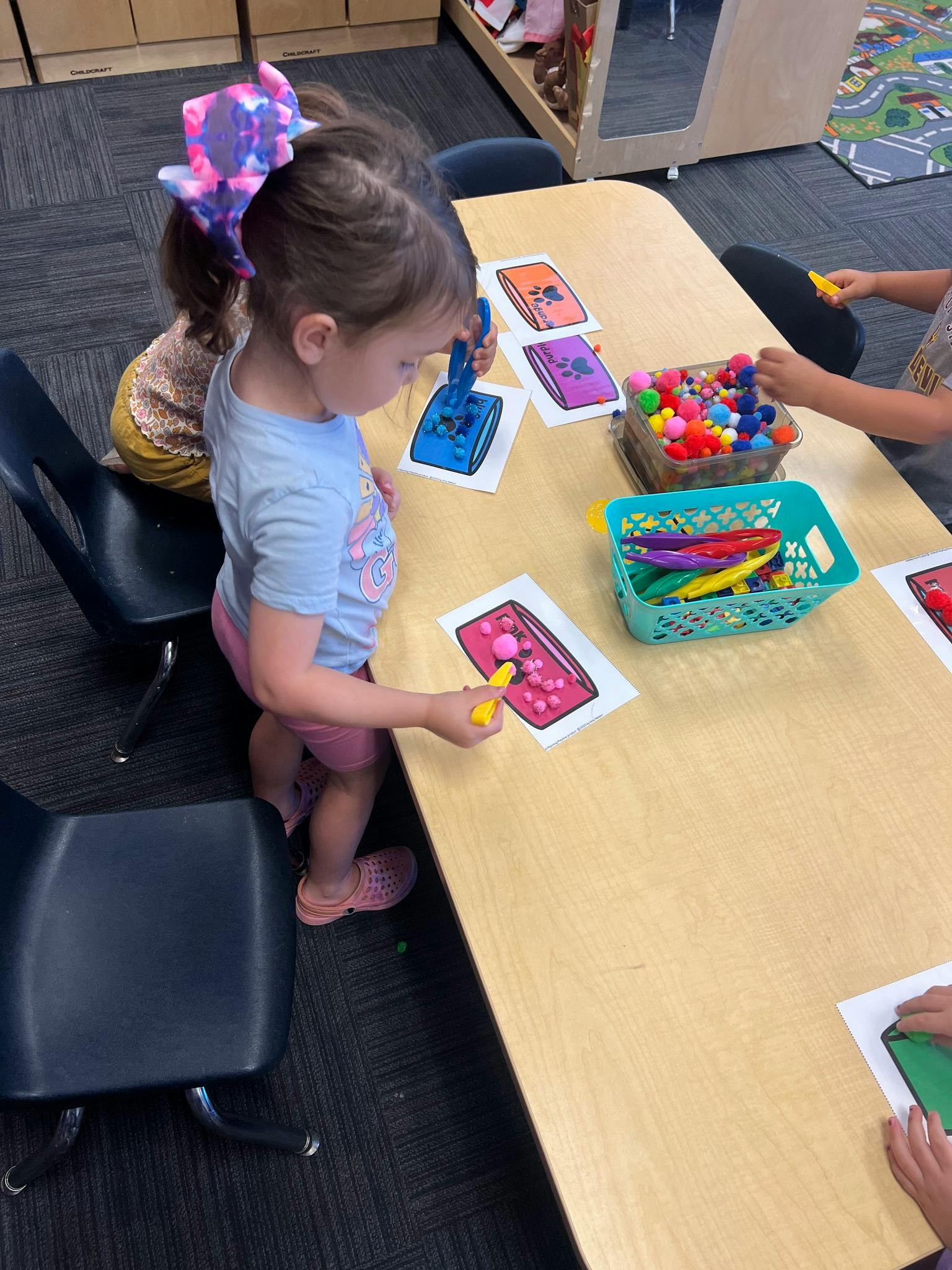 Child using a tool to place pom-poms on a paper