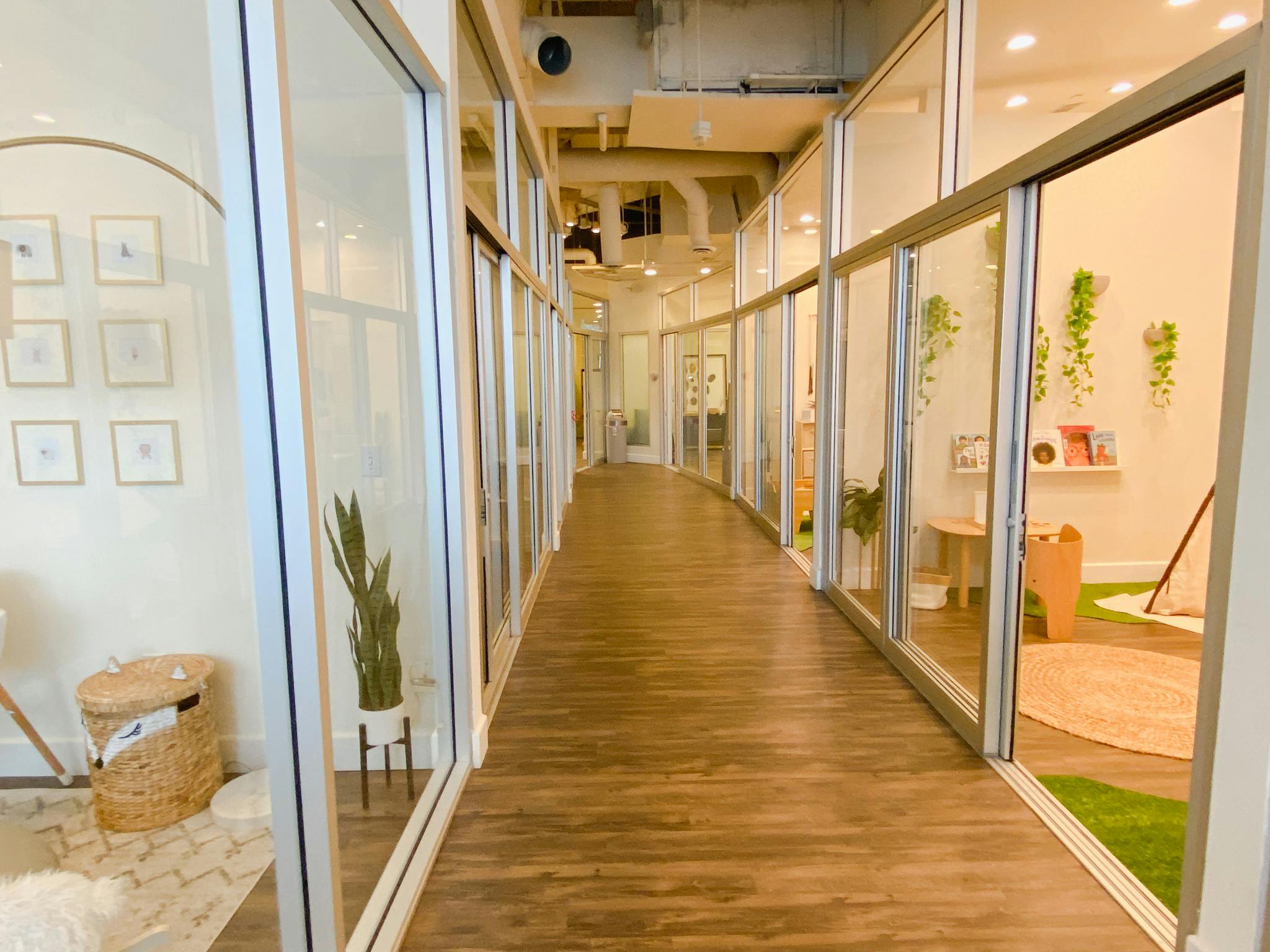 Long hallway with glass walls and wooden floor