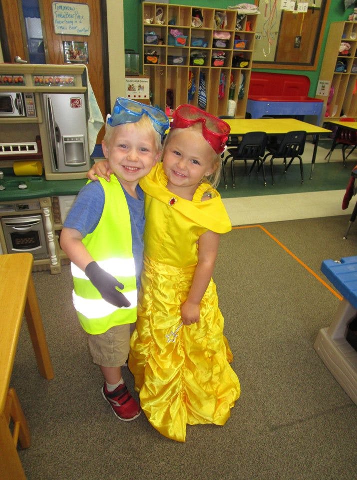 Two children in costumes posing together in a classroom