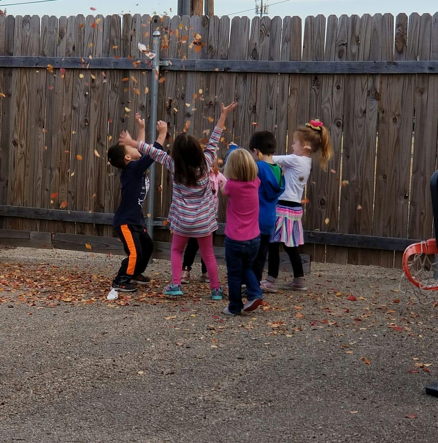 Children playing with leaves in a yard