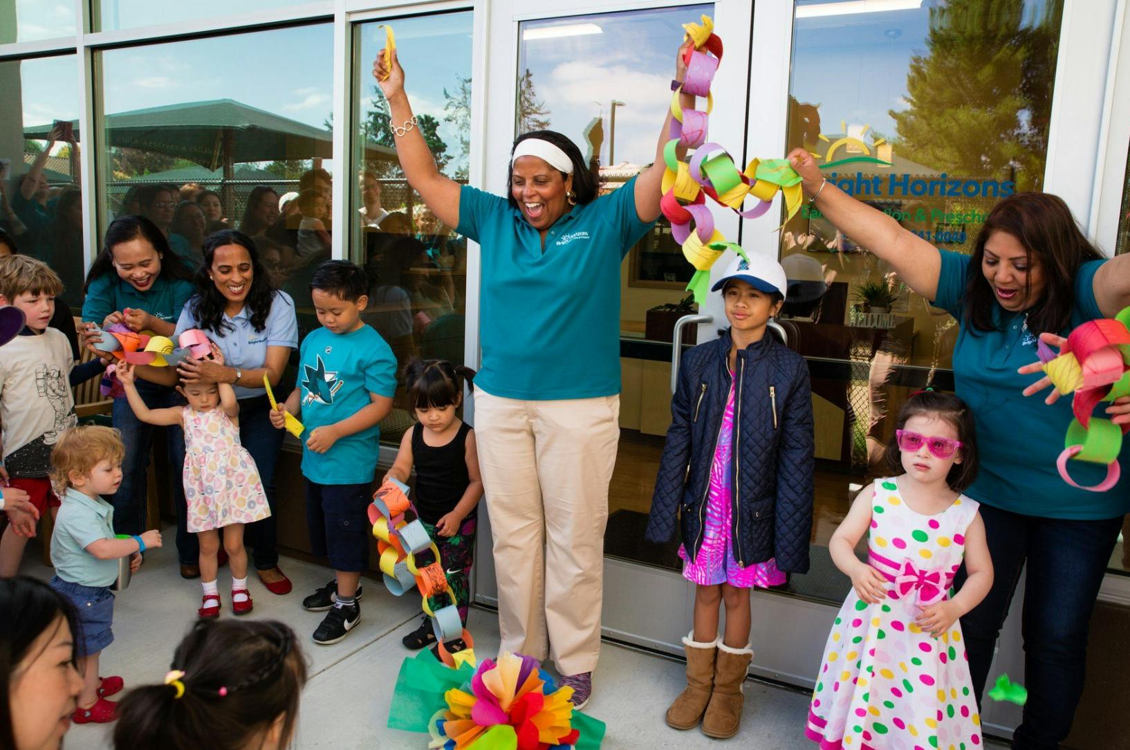 Adults and children playing with colorful paper chains outdoors