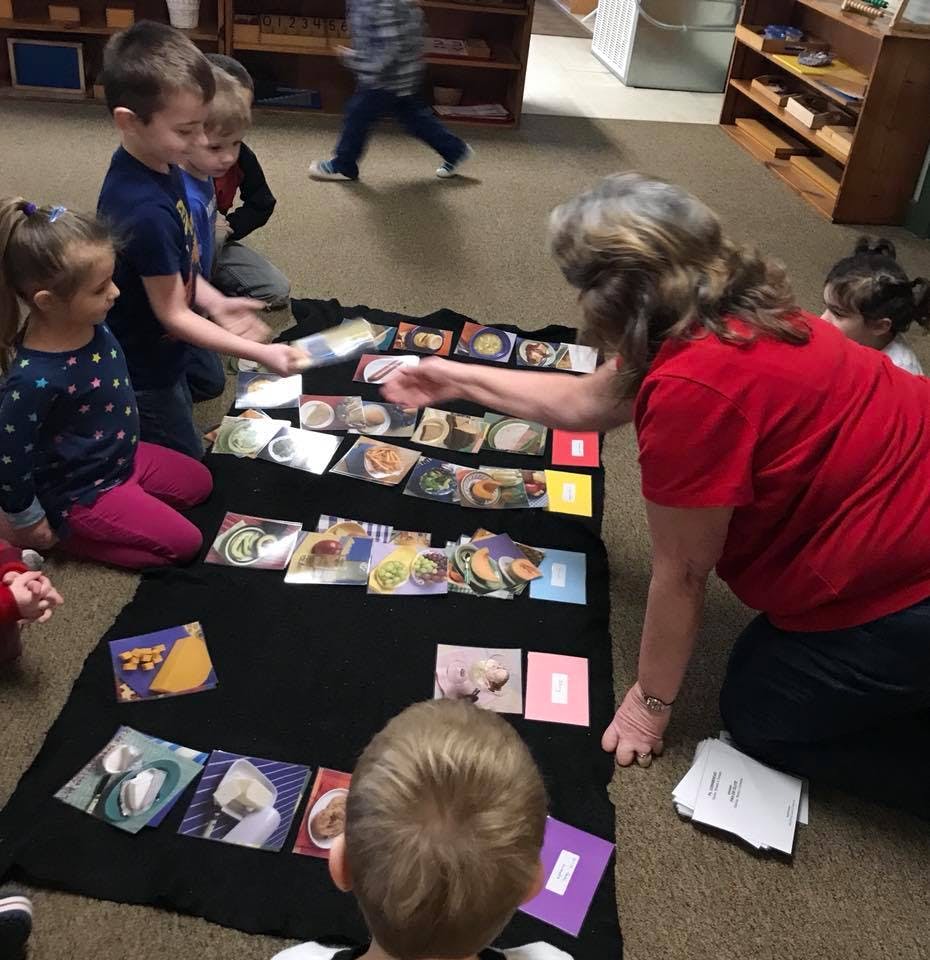 Adult and children on floor playing with cards