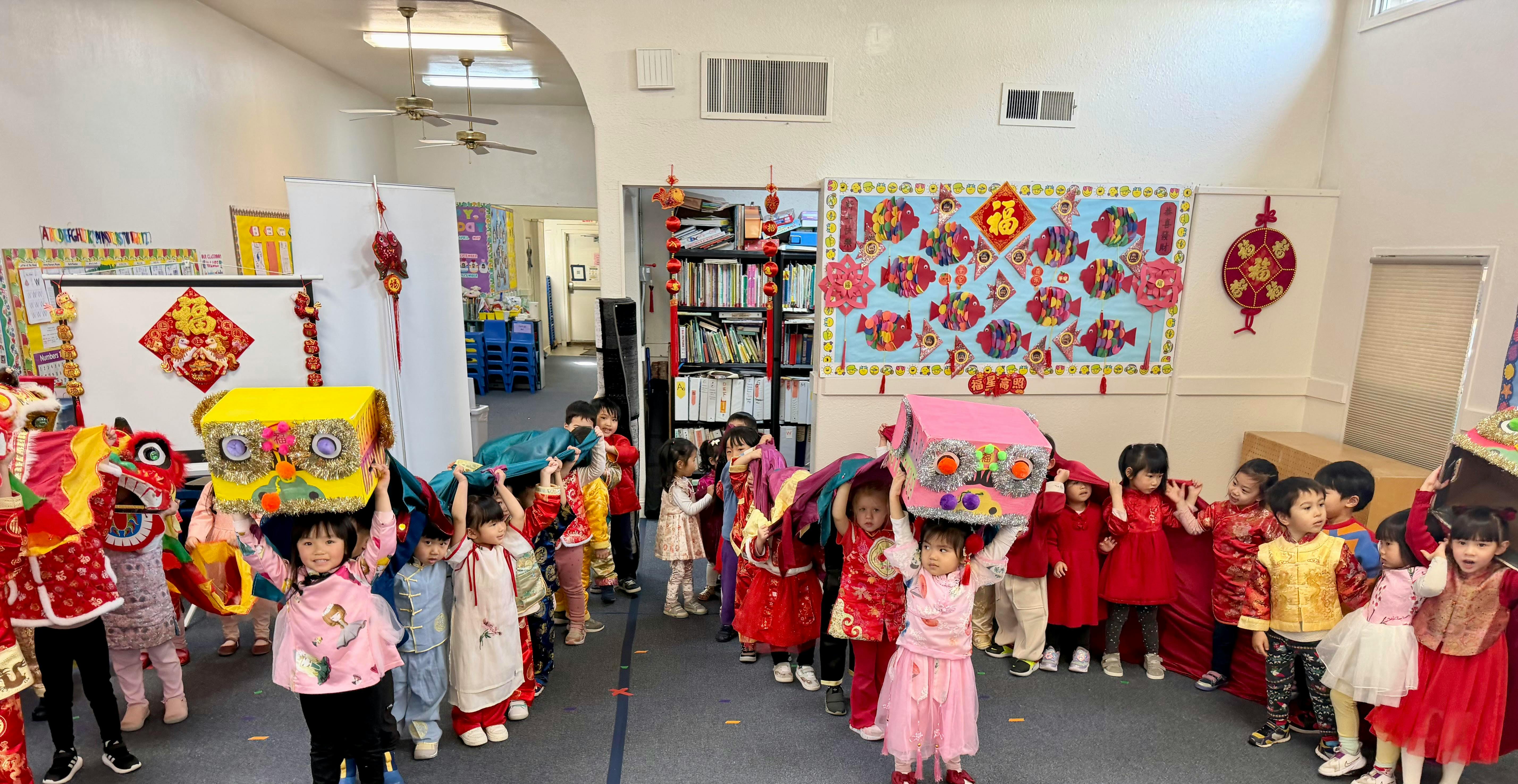 Children in traditional clothing performing a lion dance with paper props