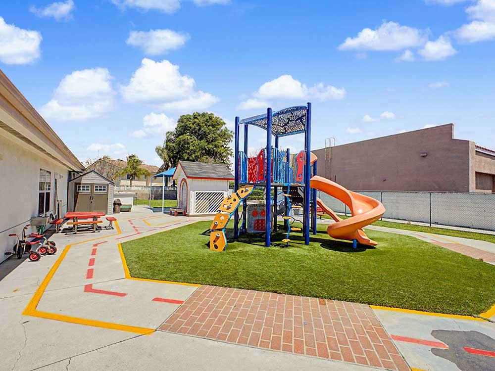A colorful playground with an orange spiral slide and picnic tables