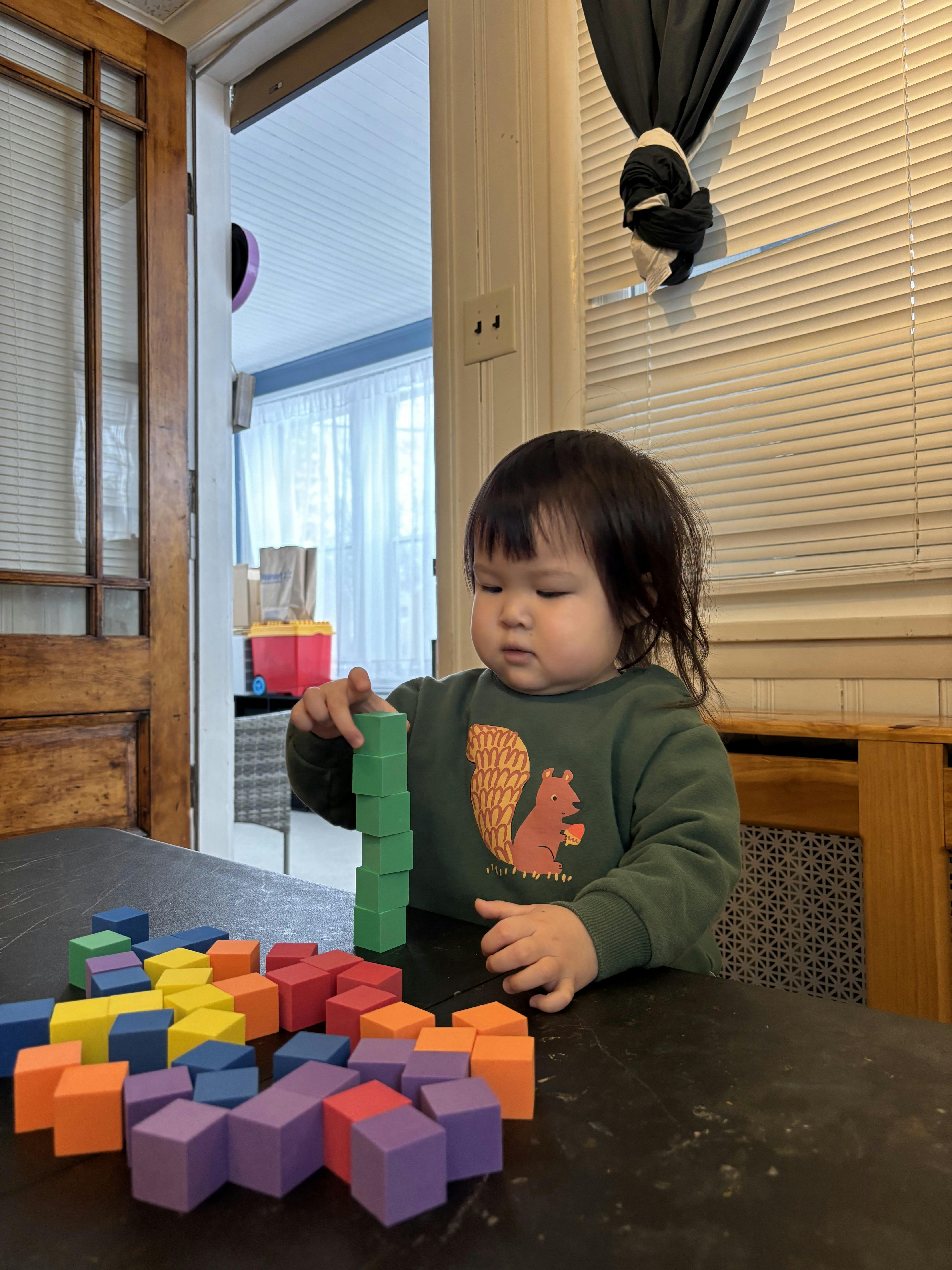 Child stacking colorful square blocks on a table