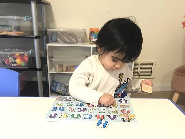 Child playing with an alphabet puzzle on a table