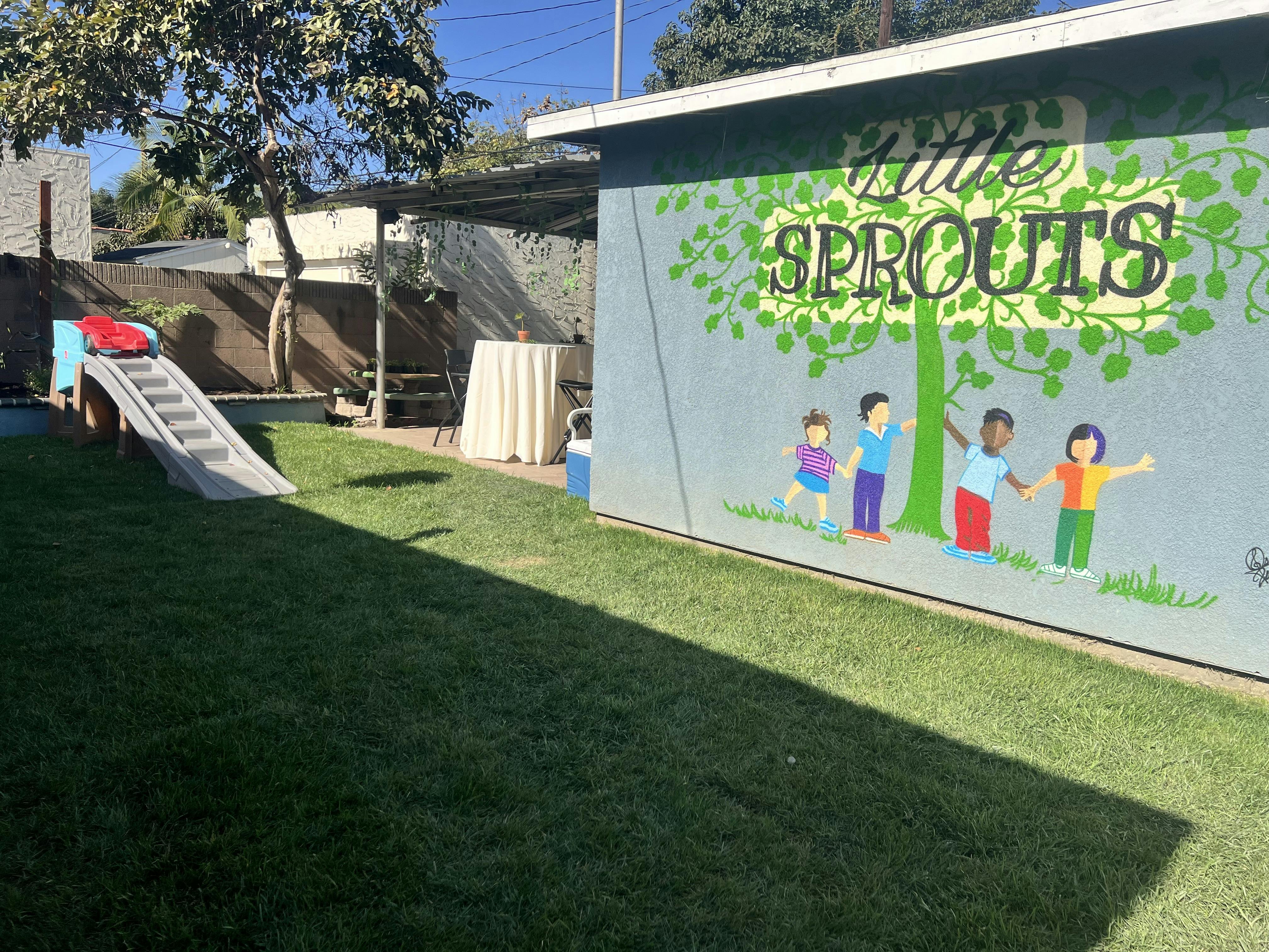 Mural of a tree and diverse children holding hands next to a play slide