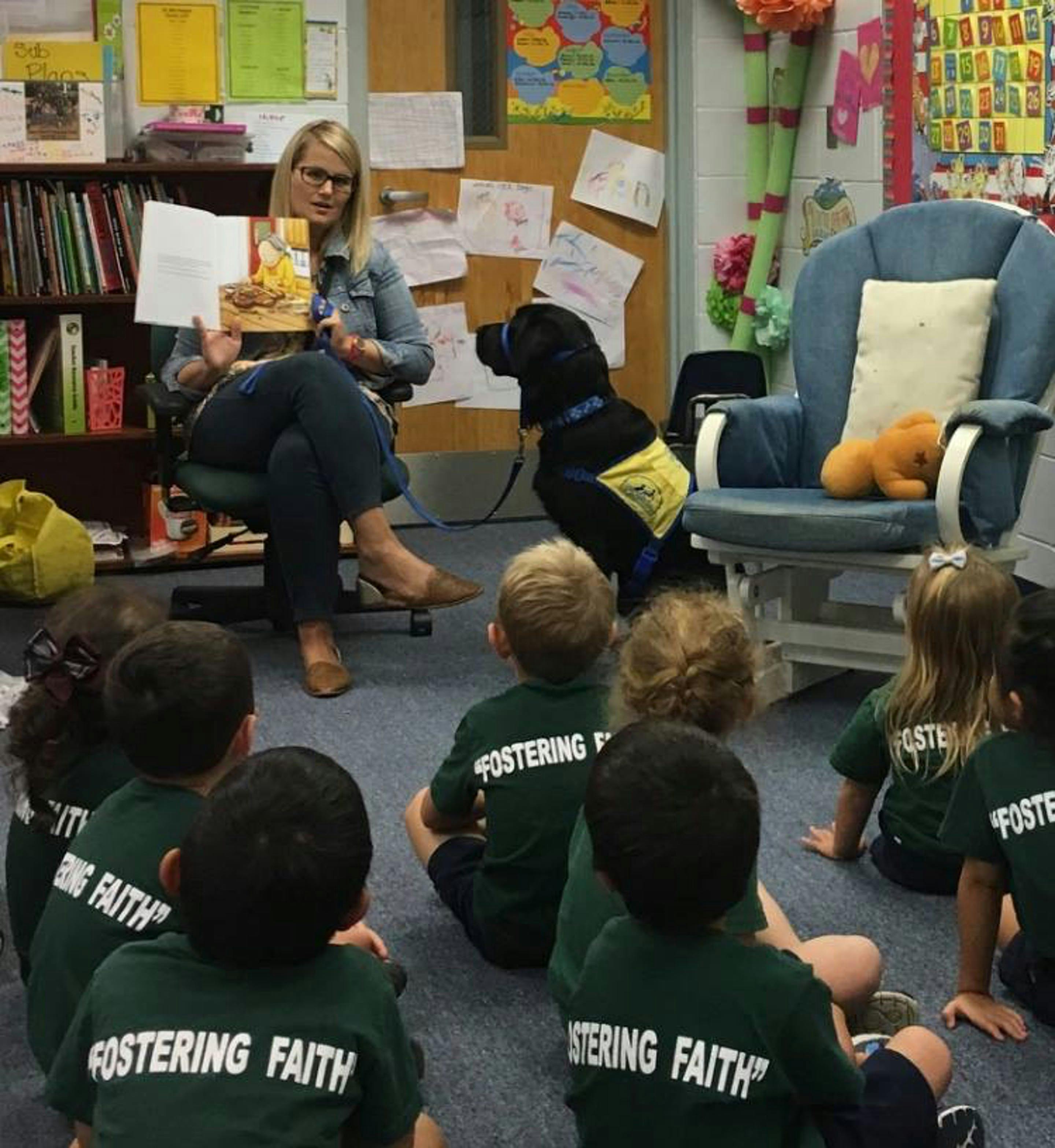 Person reading to children and a dog in a classroom