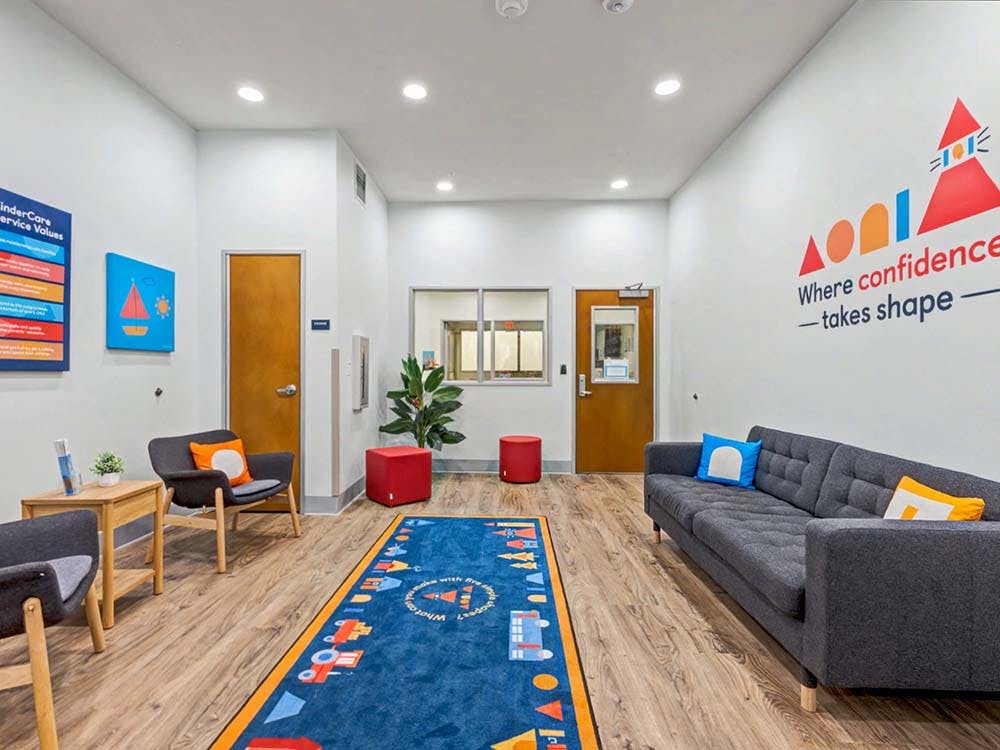 Lobby with a gray sofa, chairs, and a blue rug with a geometric pattern