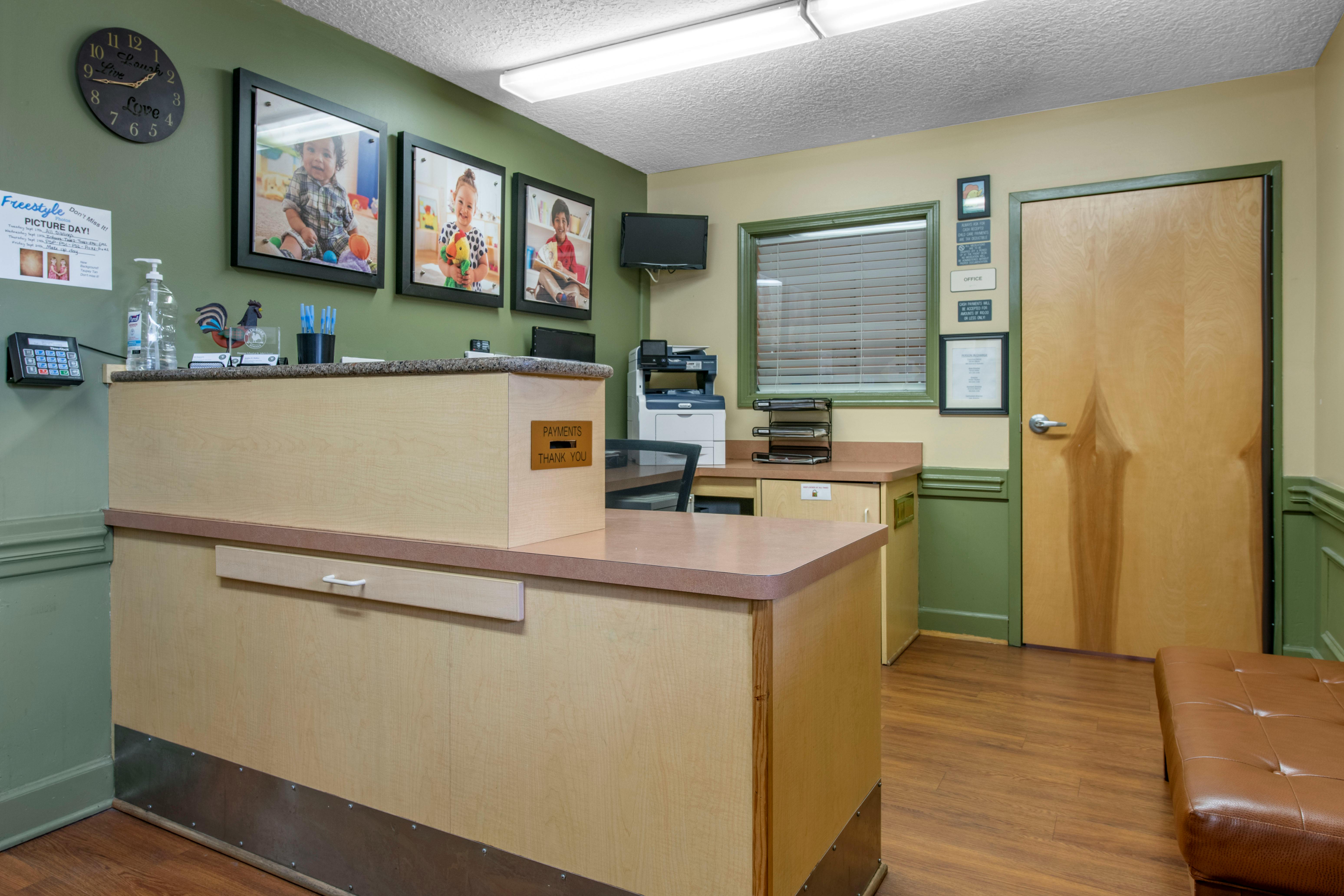 Reception desk with three framed photos of children on the wall behind it
