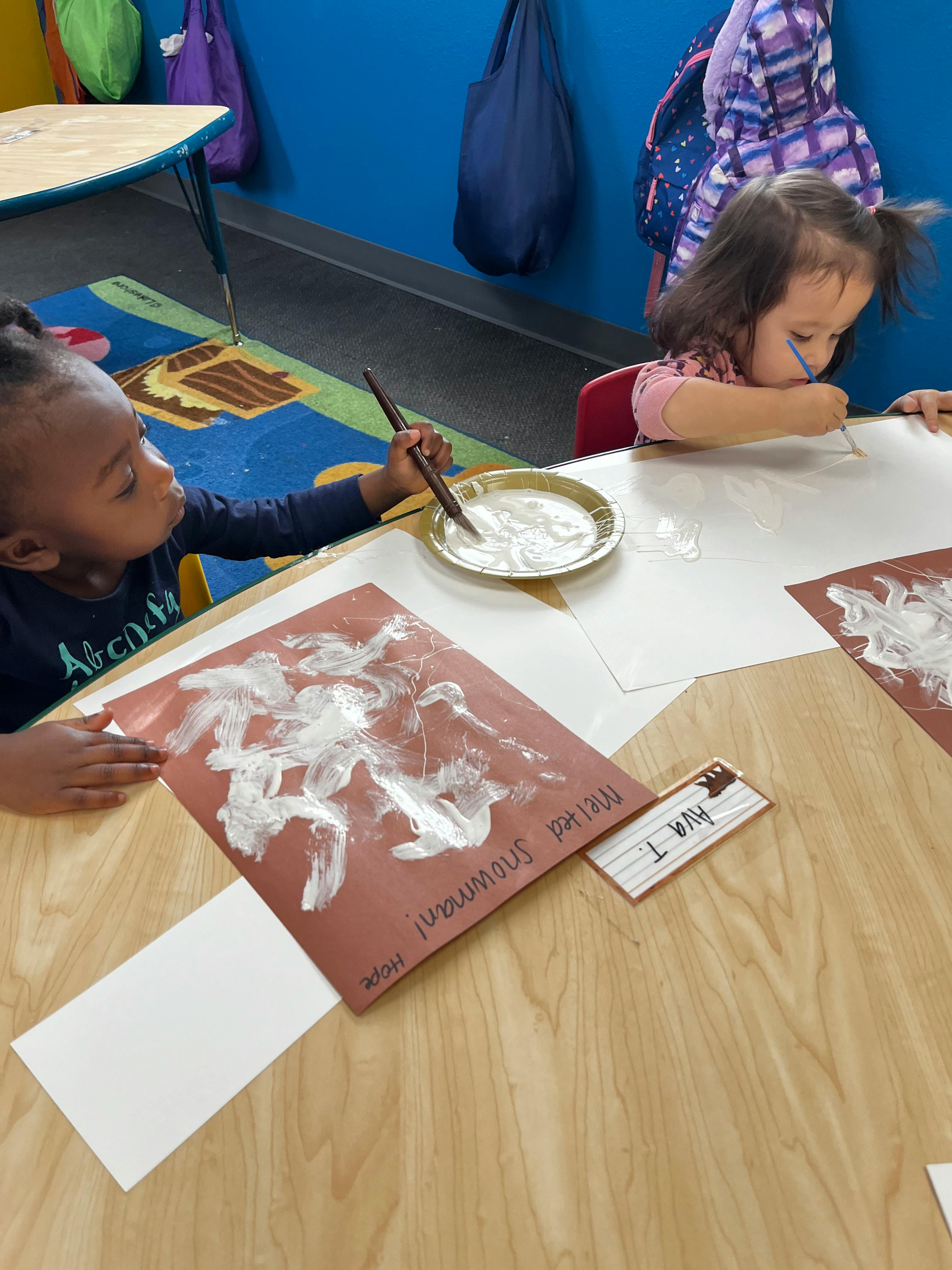 Two children painting at a table in a classroom