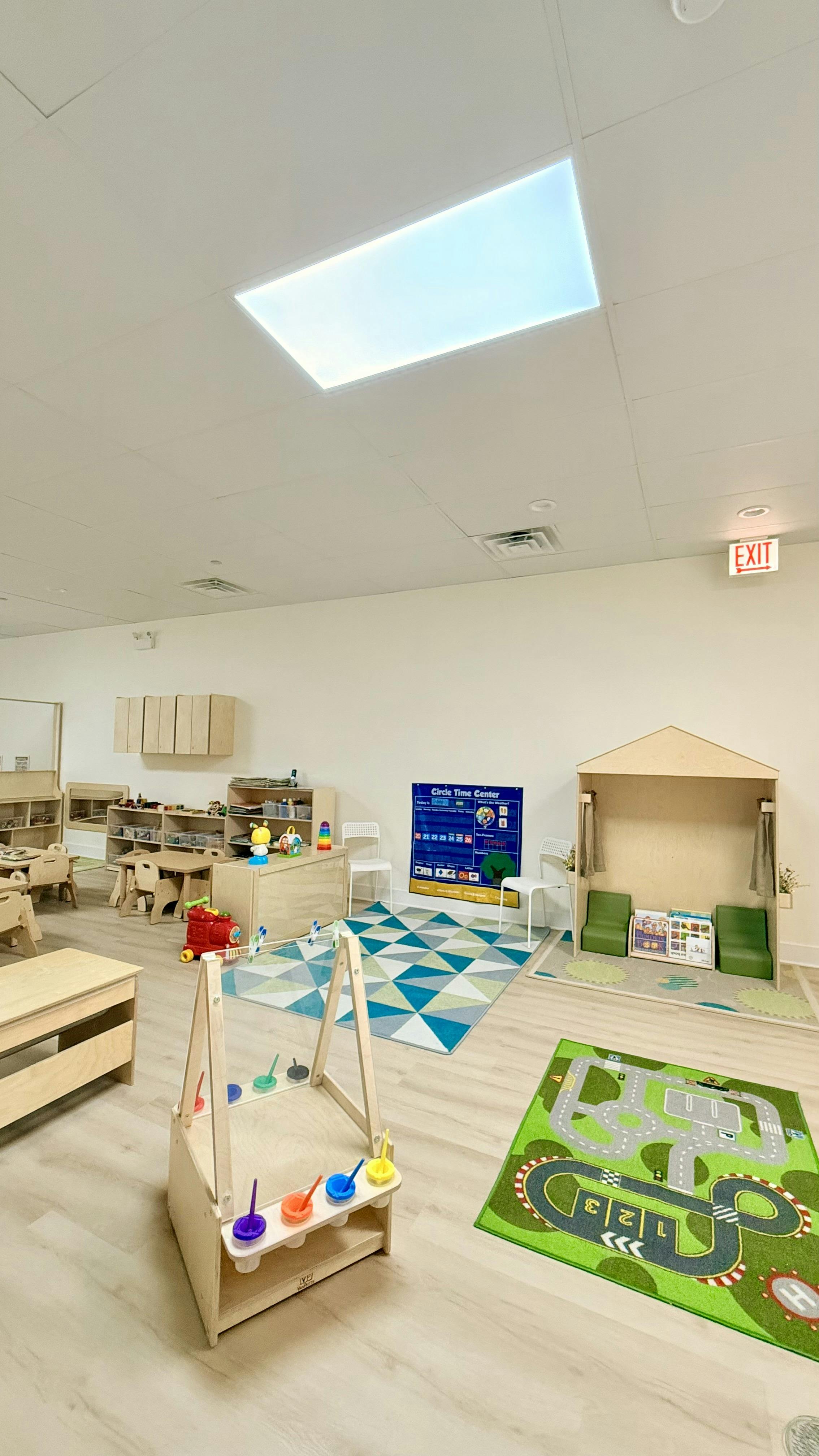 A brightly lit classroom with various play areas and furniture