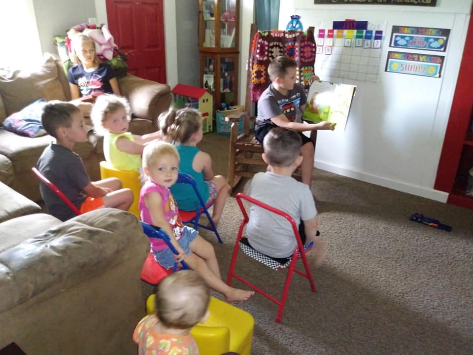 Children sitting and listening to a child reading a book