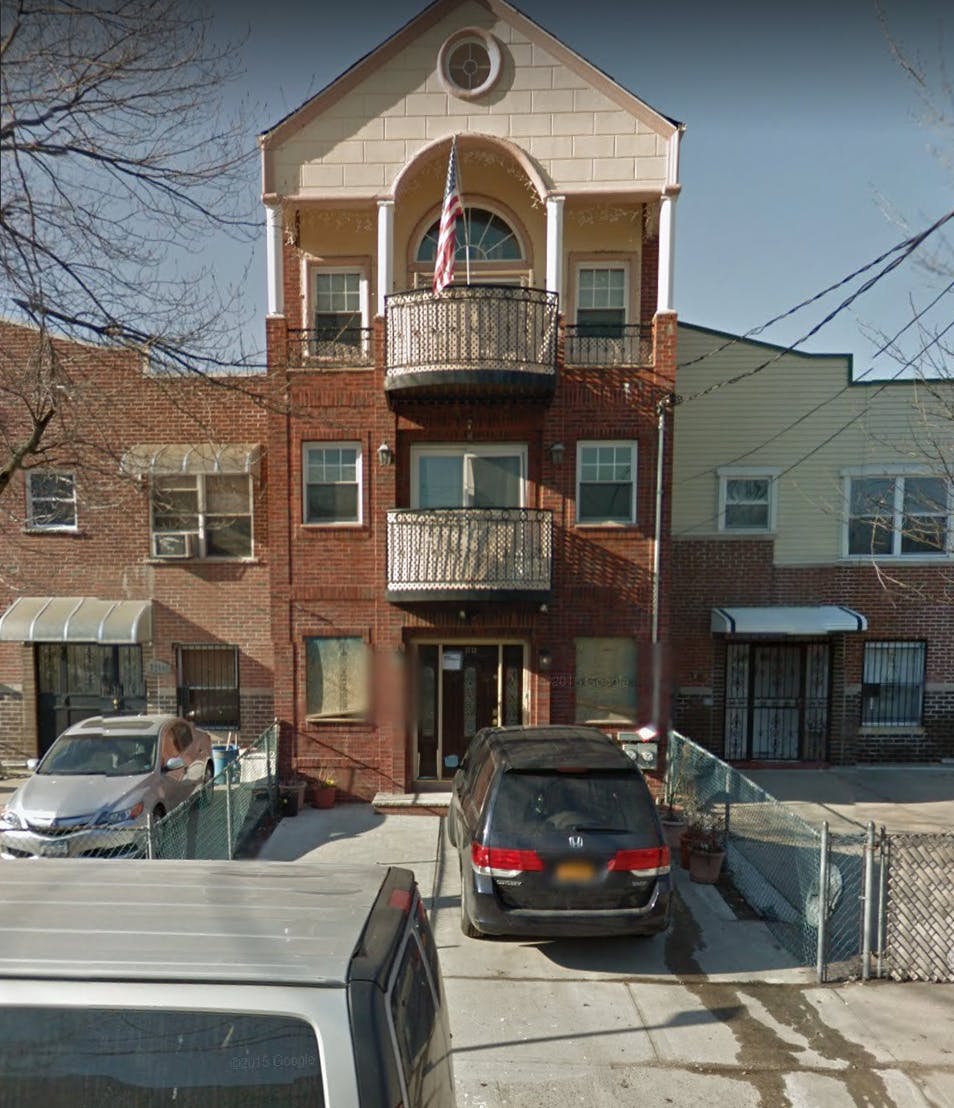 Multi-story building with balconies and cars parked in front