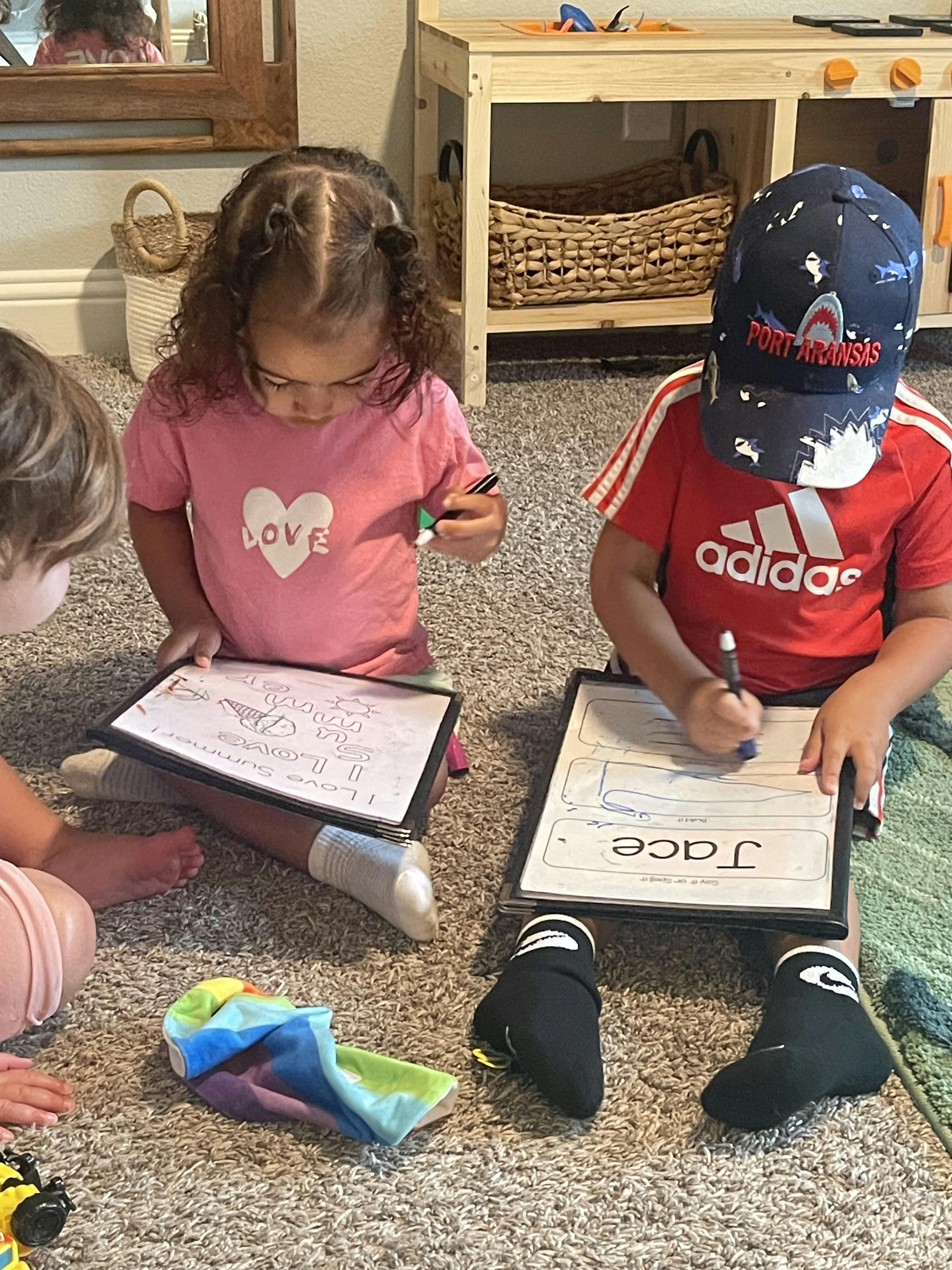 Children sitting on the floor using dry erase boards