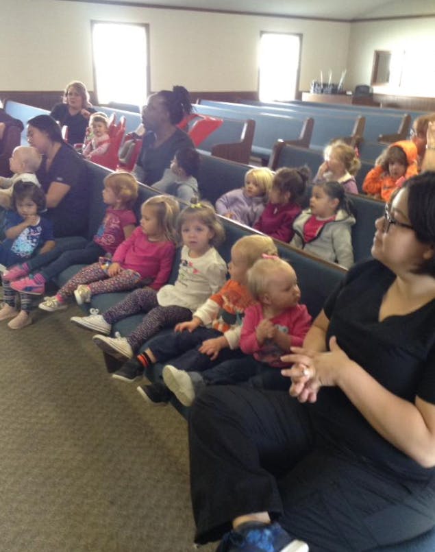 Adults and children sitting in rows of pews