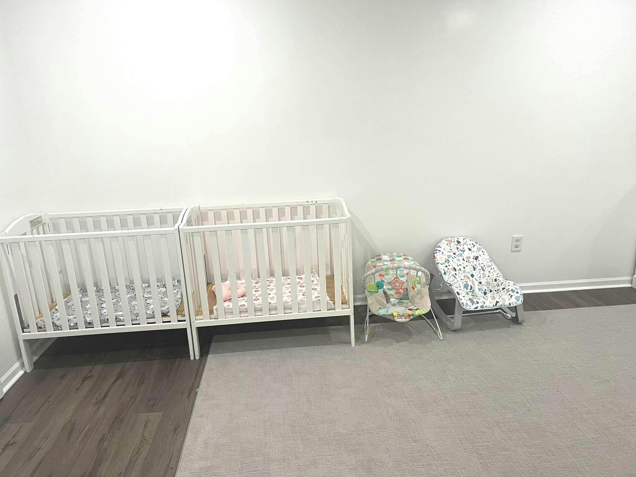 Two cribs and two baby seats in a room