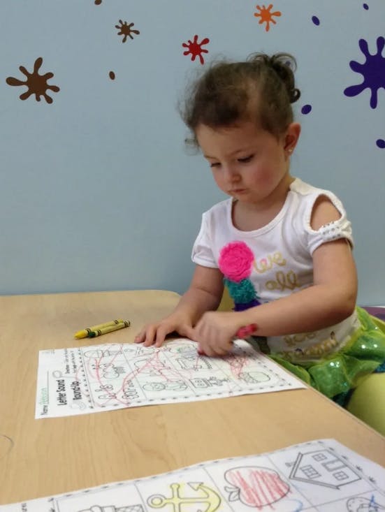 Child coloring a worksheet at a table
