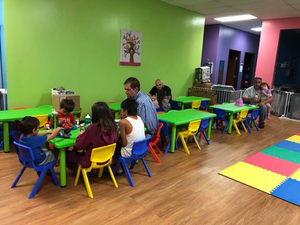 Adults and children sitting at small tables in a room