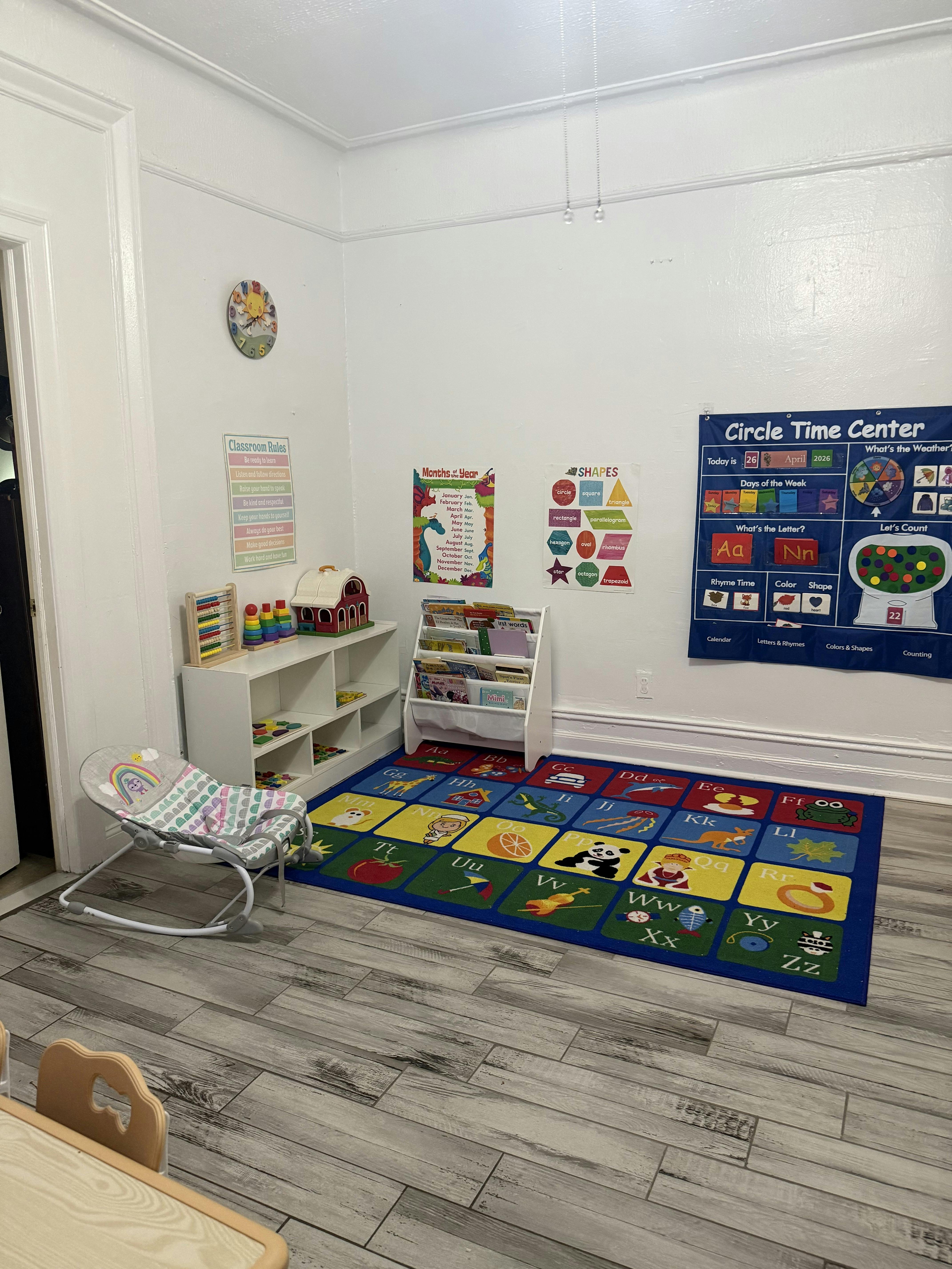 Baby bouncer in a classroom with an alphabet rug and learning charts