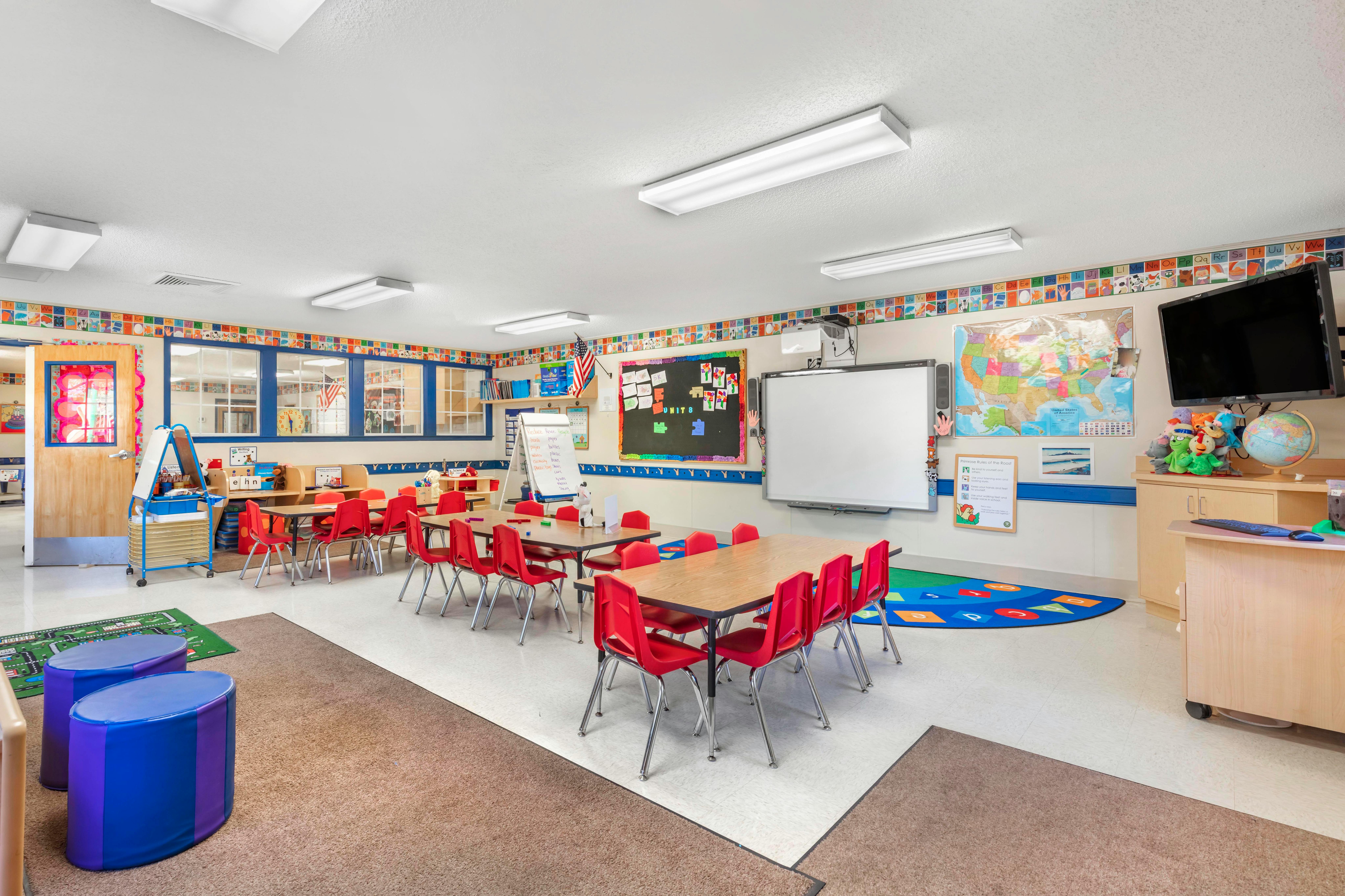 Classroom with small tables, red chairs, and alphabet decorations on the wall