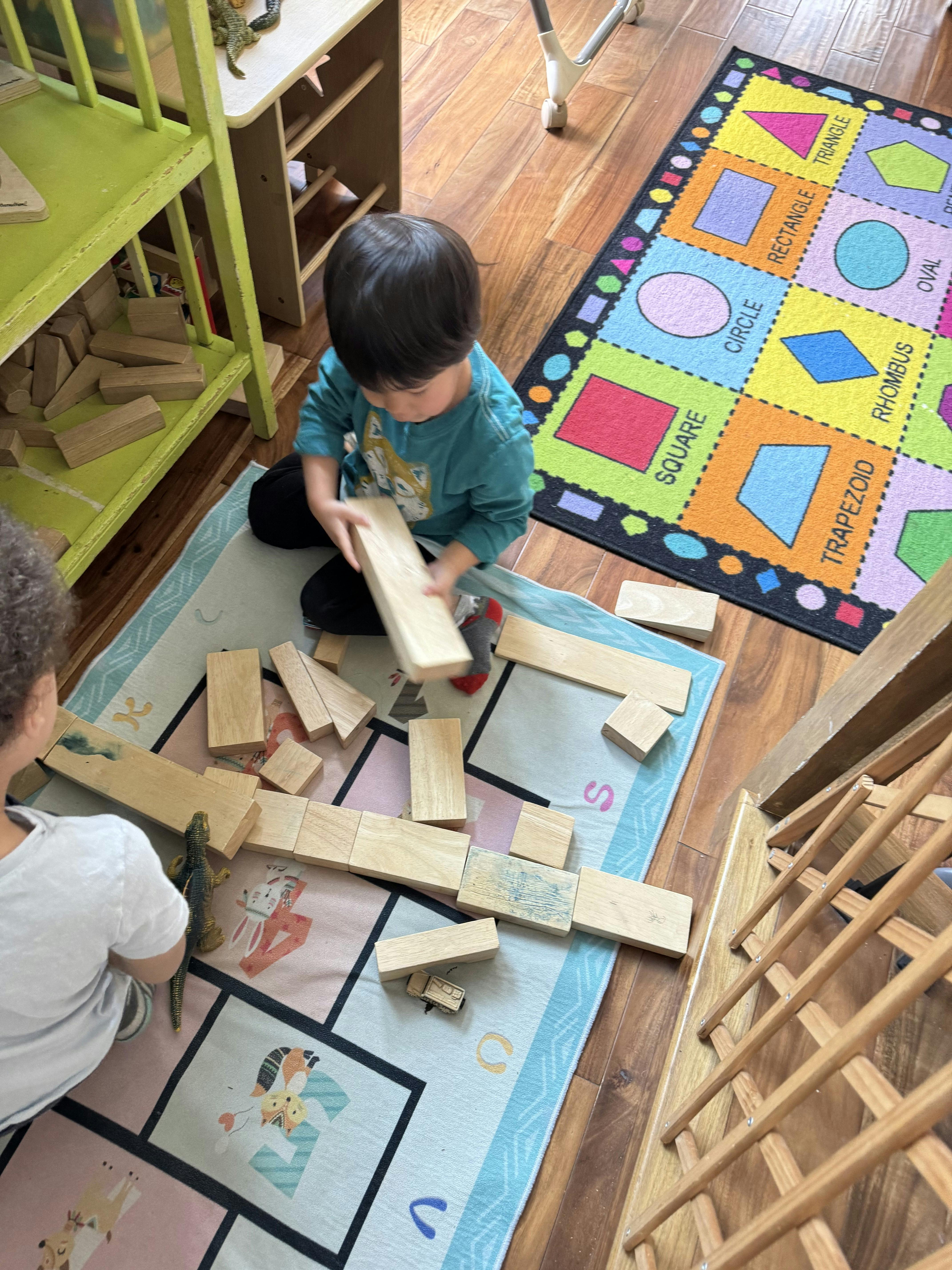 Children playing with wooden blocks on a rug
