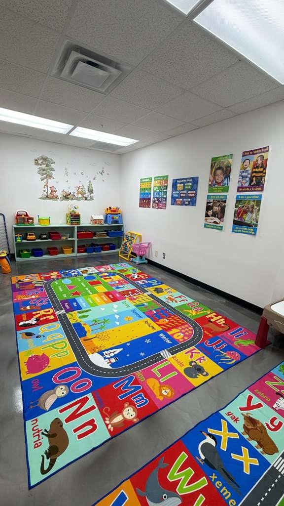 Children's classroom with colorful alphabet rug and shelves of toys