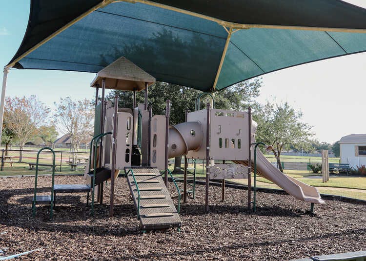 Playground structure with slides and stairs under a large shade canopy