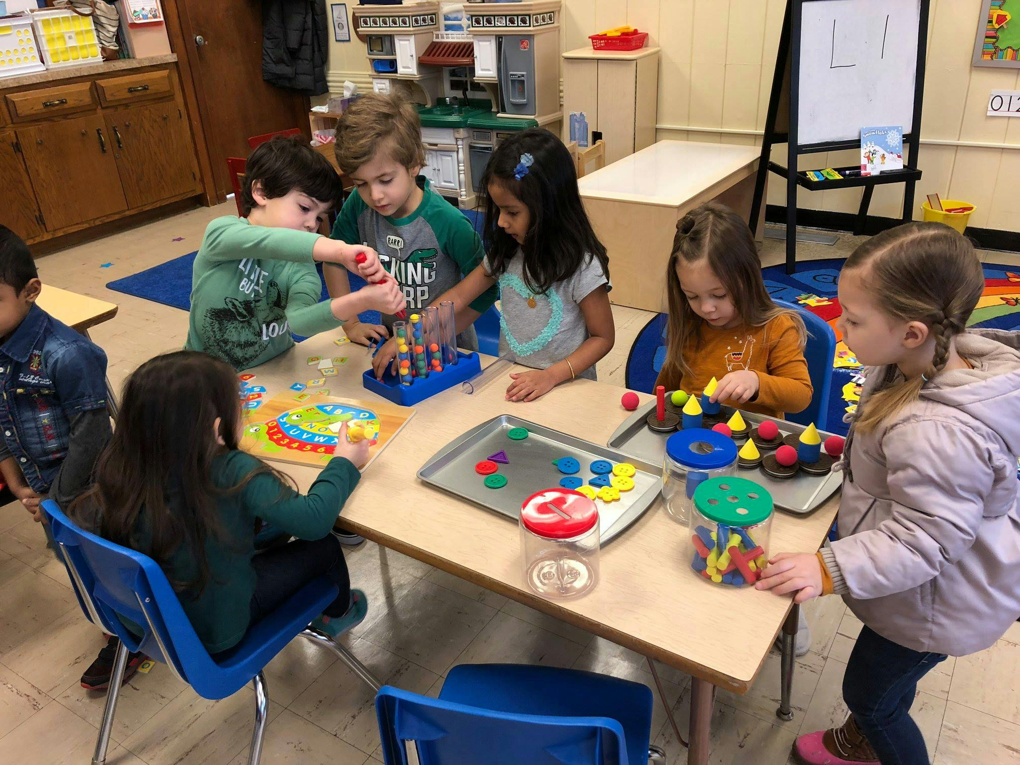 Children playing with colorful learning toys at a table in a classroom