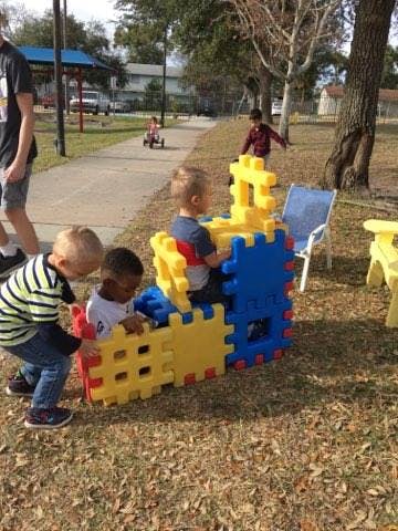 Children playing with large interlocking blocks outdoors