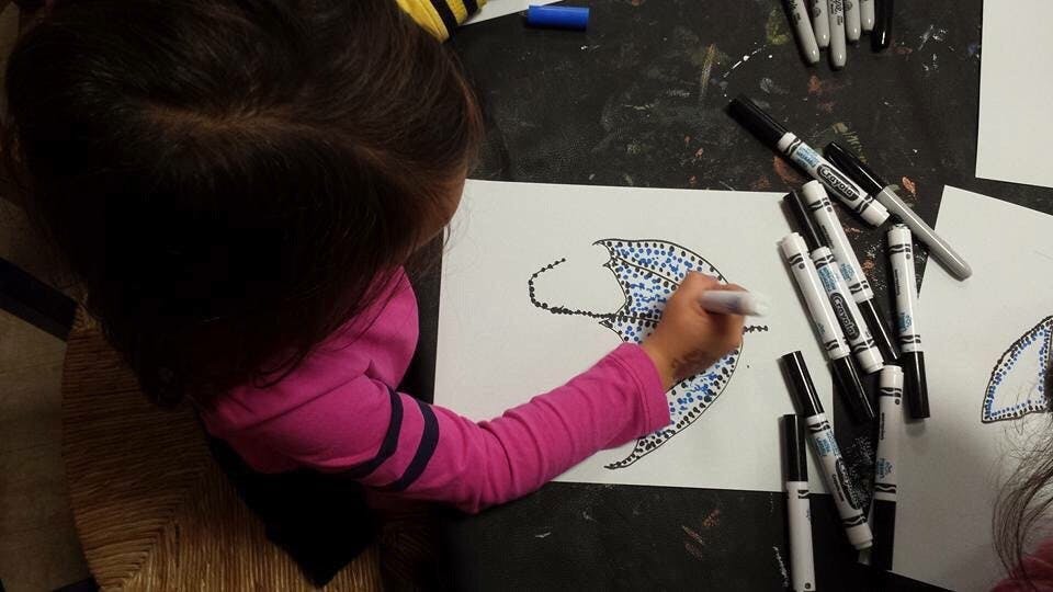 Child drawing on paper with a marker