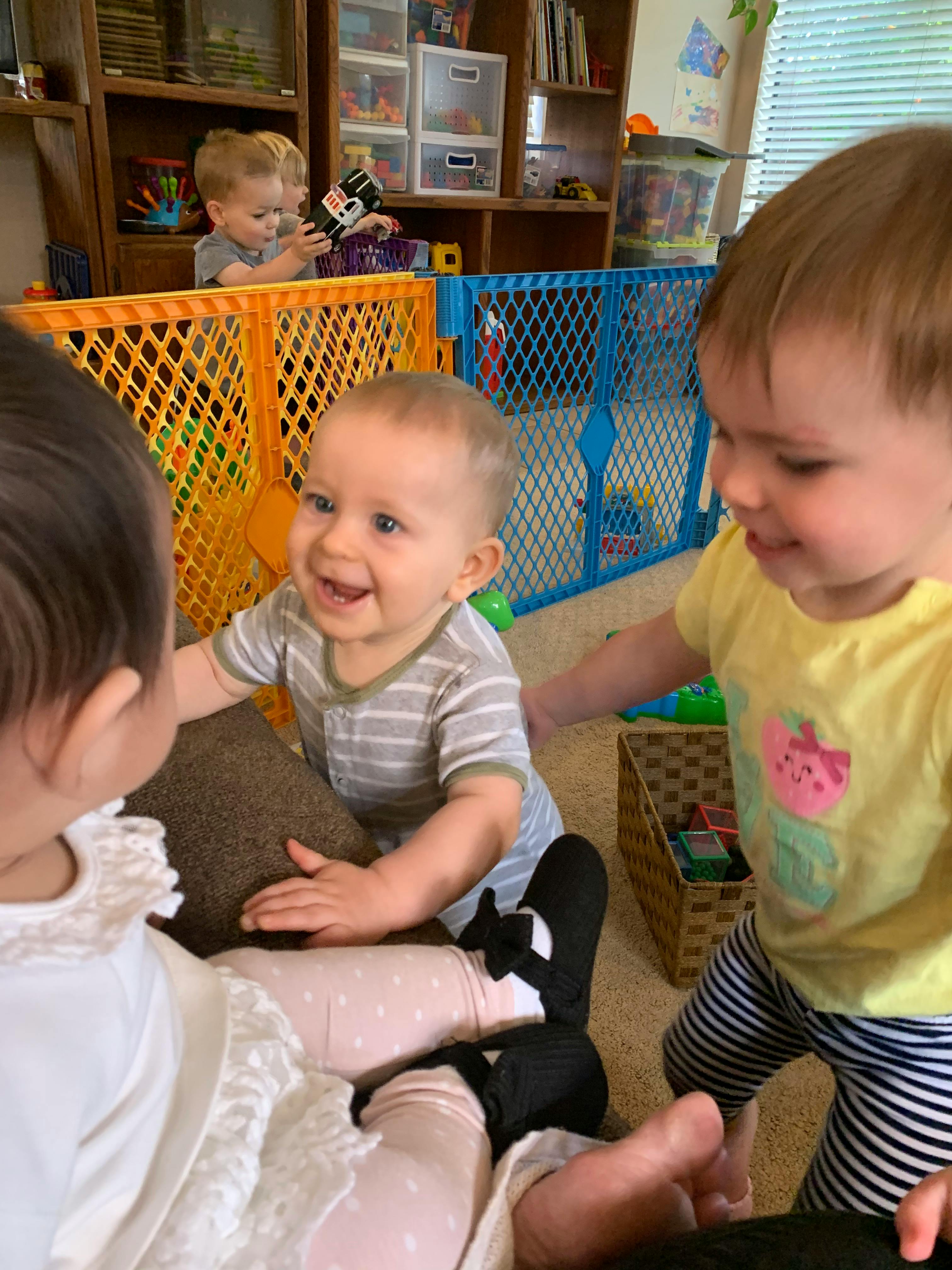 Three children playing on the floor, one smiling at another
