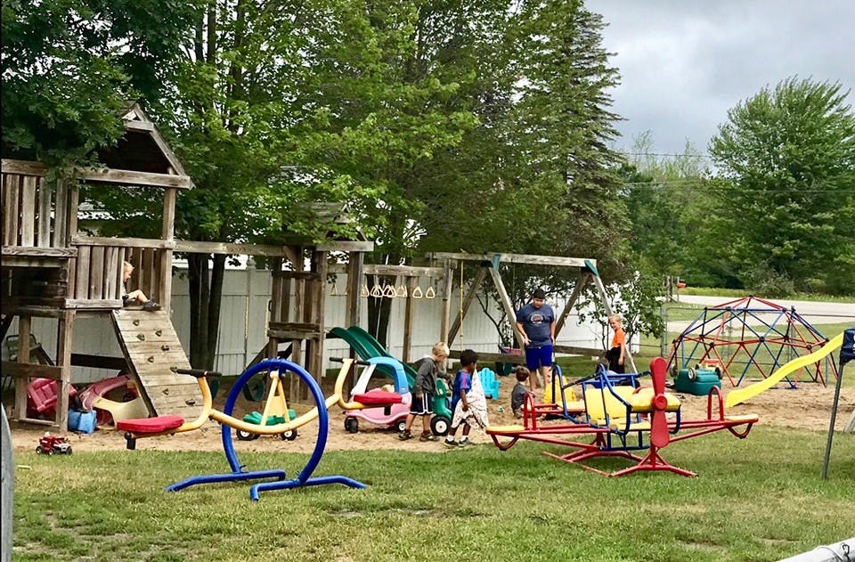 Children playing on a playground with swings, slides, and a climbing dome