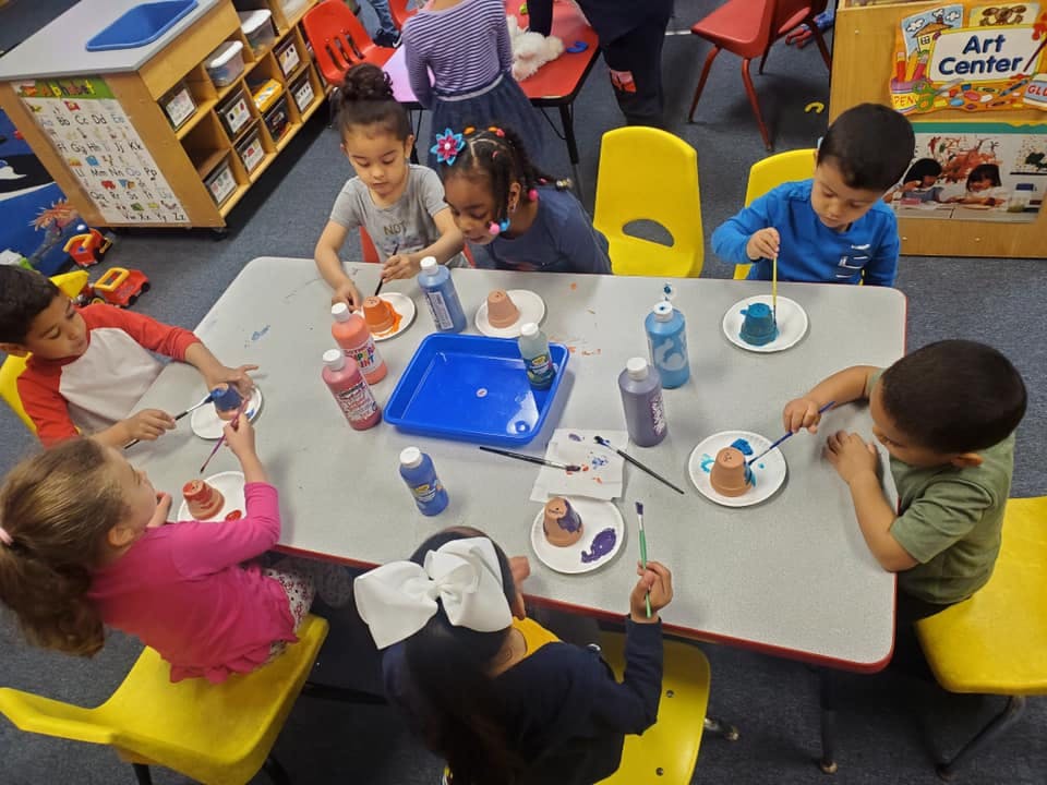 Children painting at a table in a classroom
