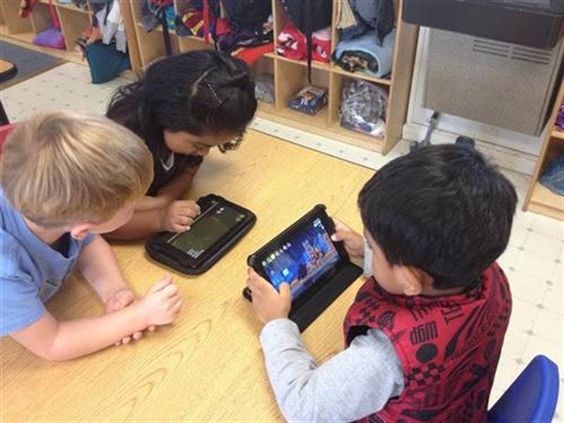 Three children looking at tablets in a classroom