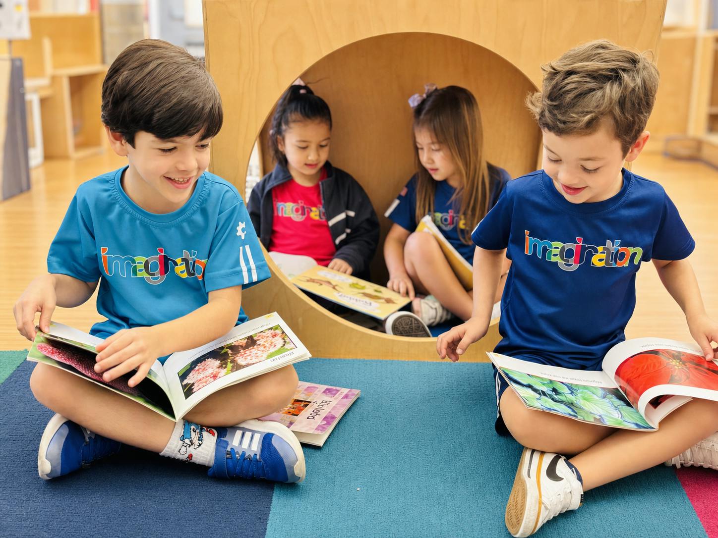 Four children sitting on the floor reading books in a classroom